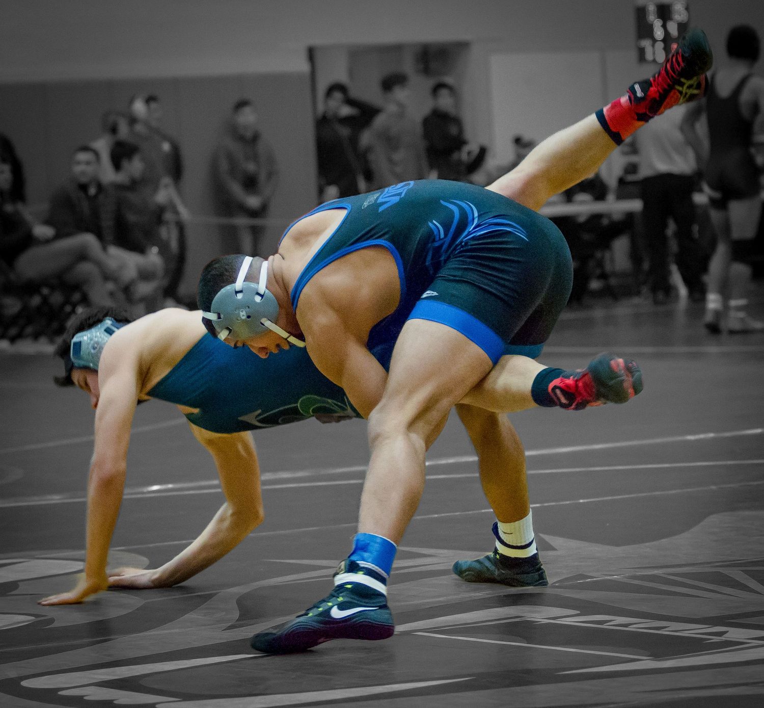 Wrestlers demonstrate technical moves during a competitive match on the mat.