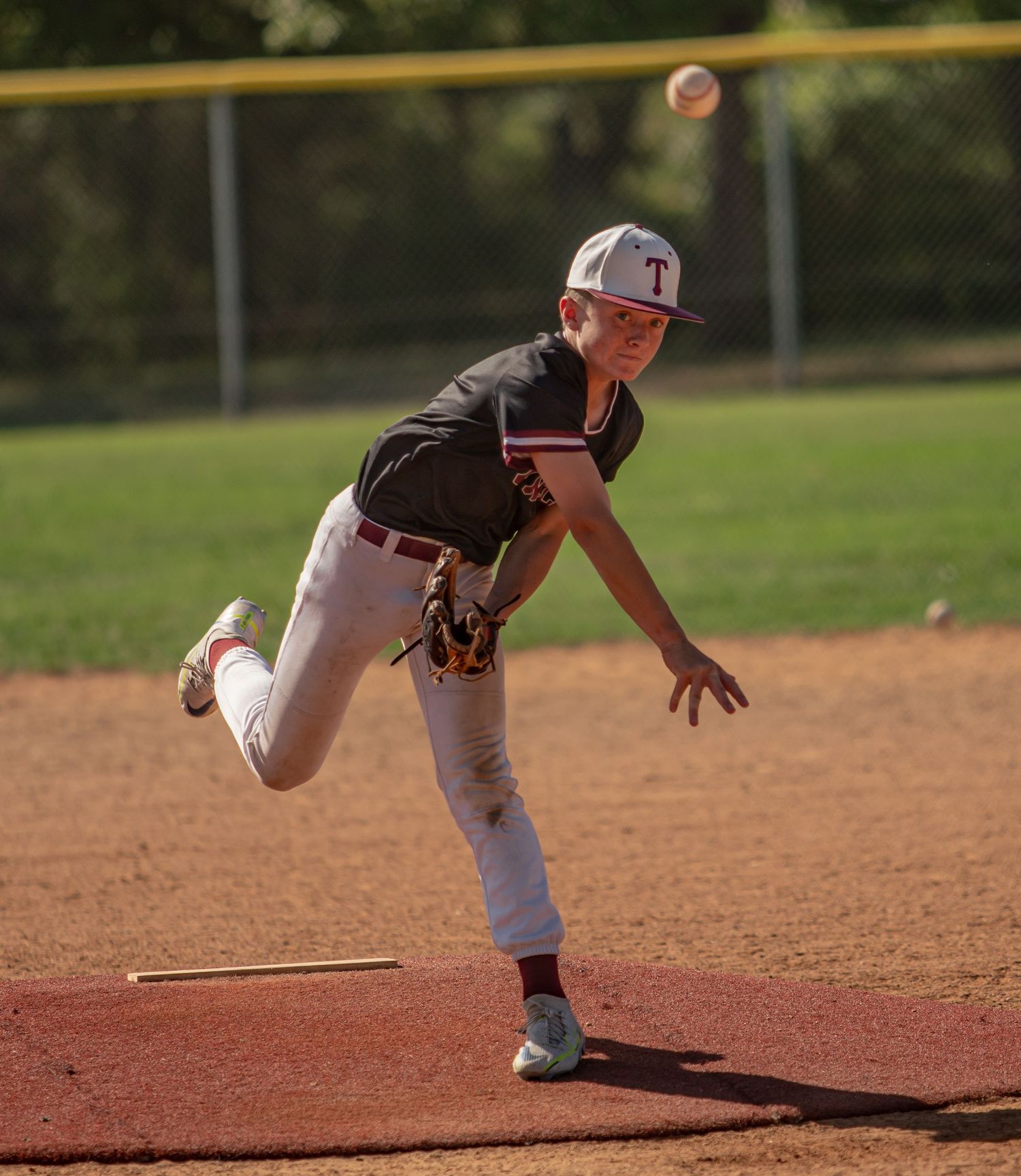 Pitcher in mid-delivery motion throwing baseball from mound during game.