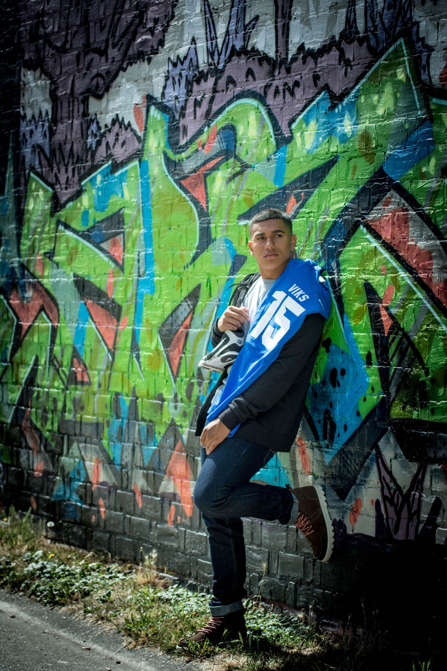Sports themed photoshoot featuring casual poses against colorful street art wall.