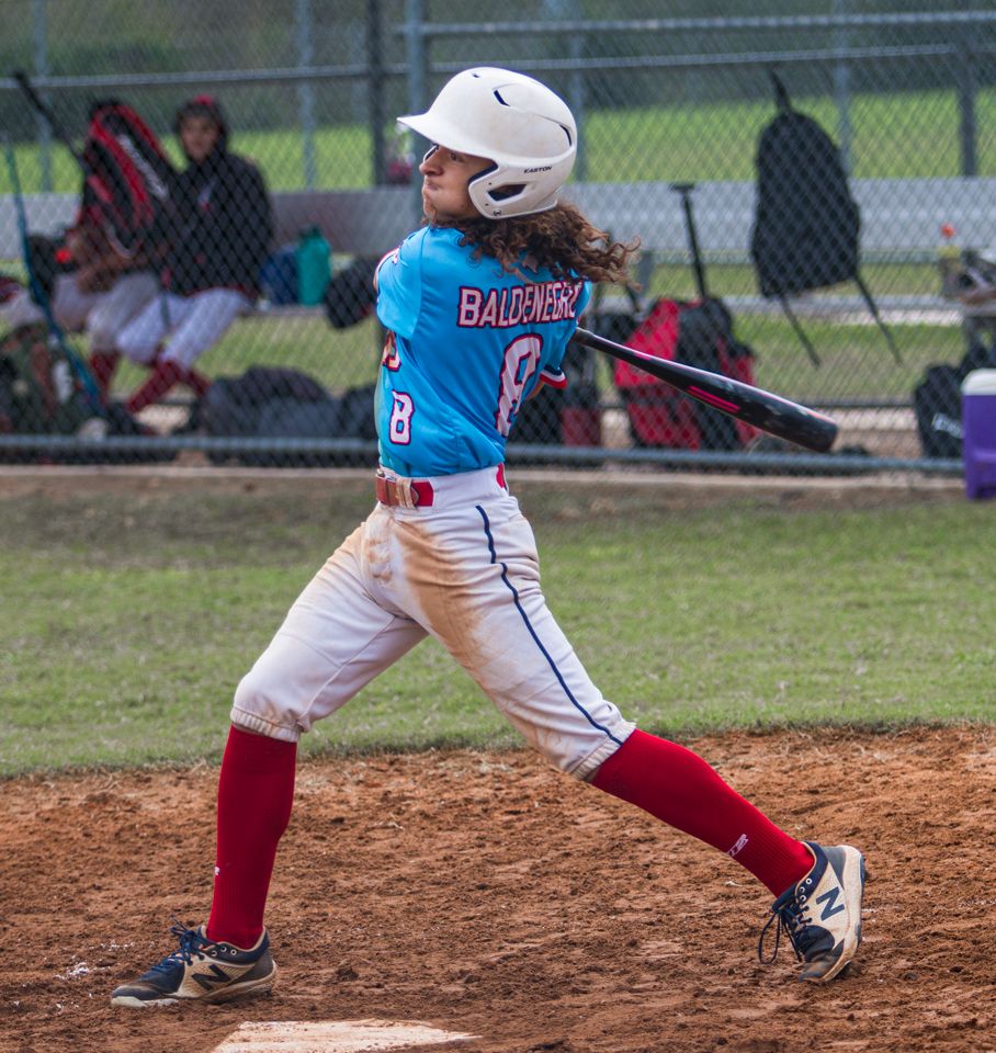 Close-up of baseball player's legs in red and white uniform during batting stance on dirt field.