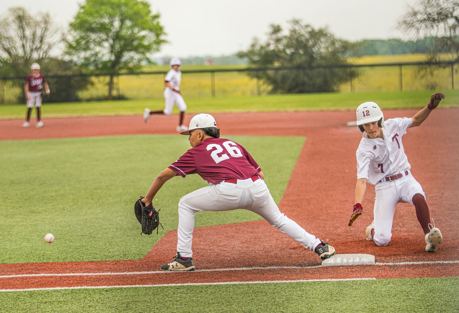 Baseball fielder stretches to make a play at first base as runner approaches.