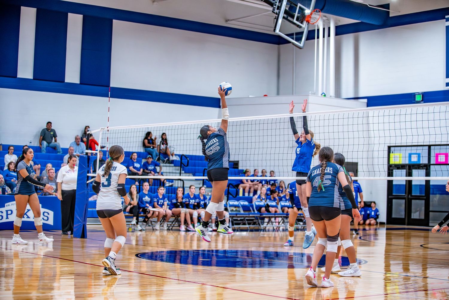 Panoramic view of indoor volleyball court with players and spectators during competitive match.