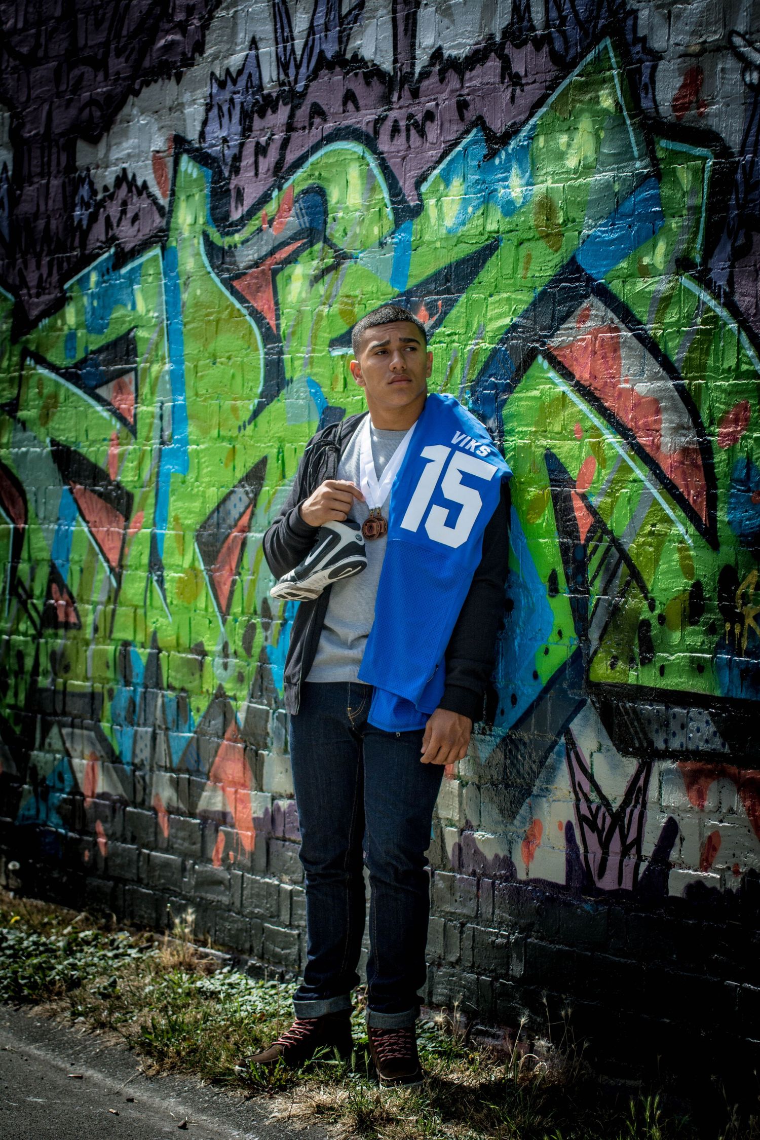 Athletic portrait session showcasing dynamic poses against vibrant graffiti mural.