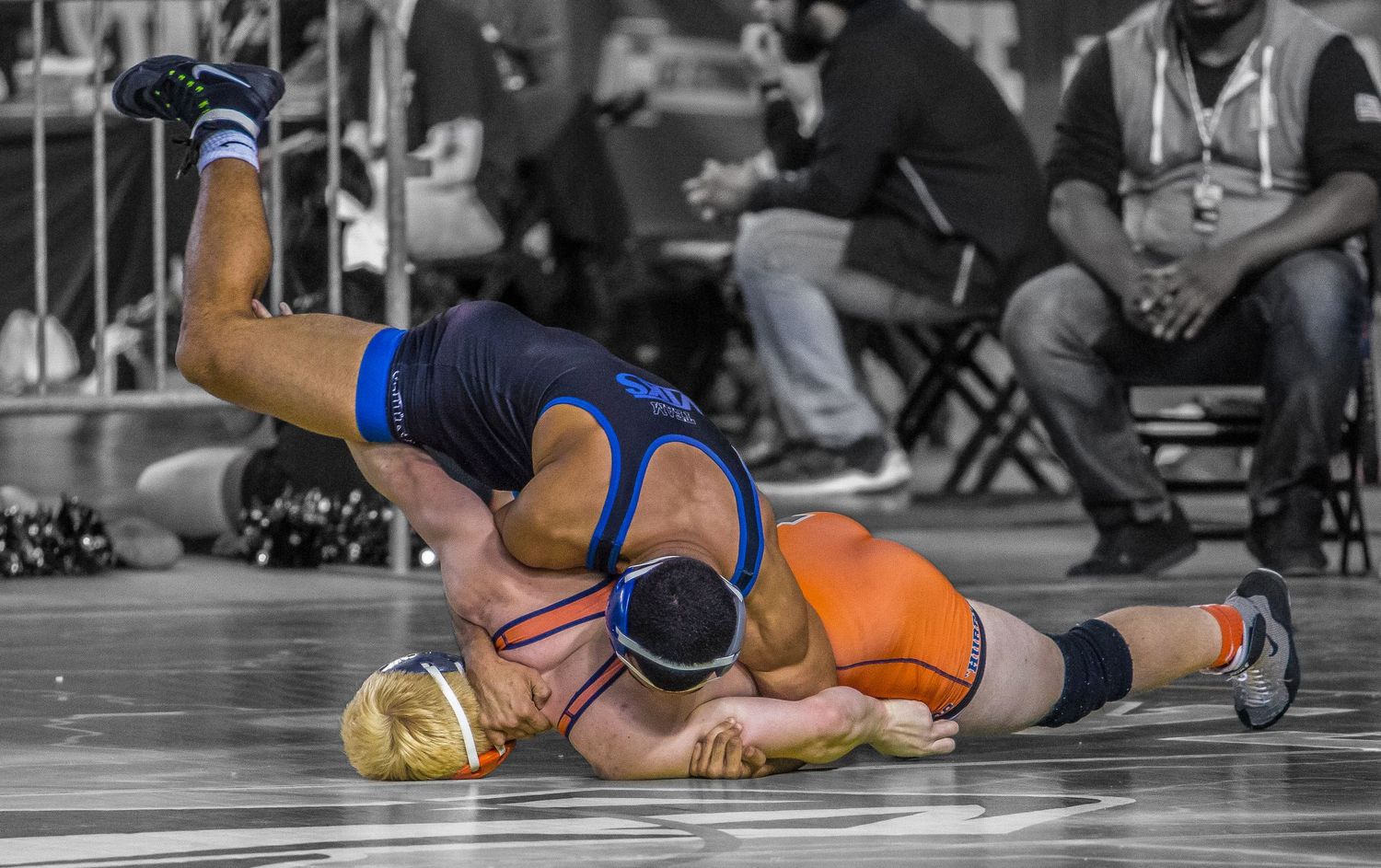 Wrestling competition featuring athletes in various grappling positions on the mat.