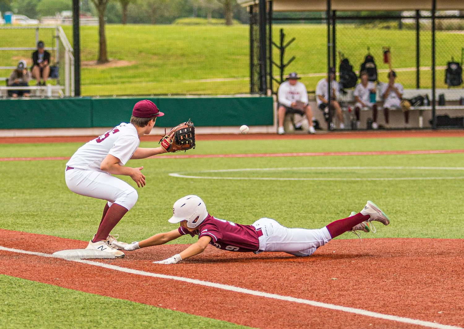 Baseball player in white uniform attempts to tag runner sliding into base during game.