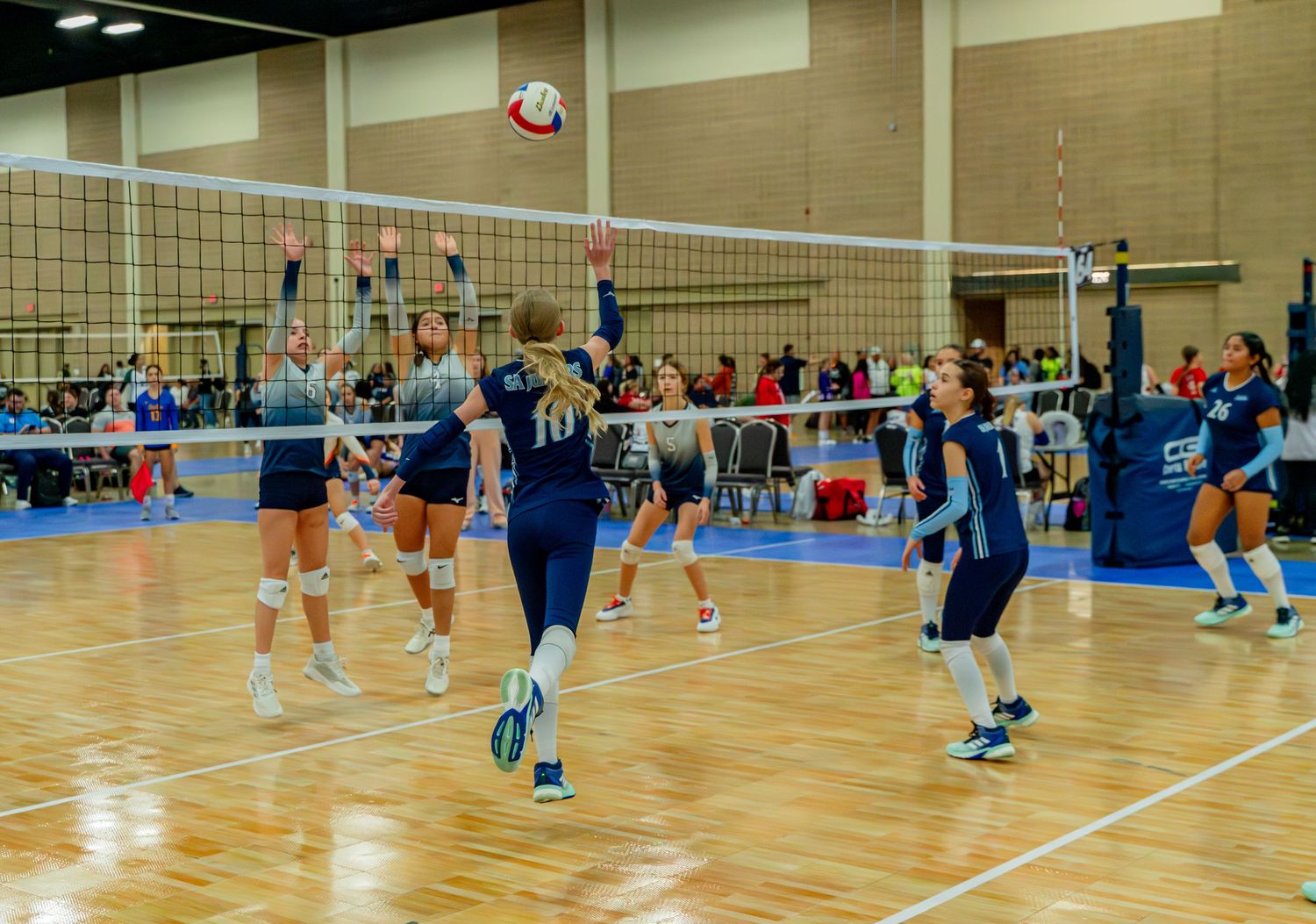 Long shot of multiple volleyball courts with teams playing simultaneous matches.