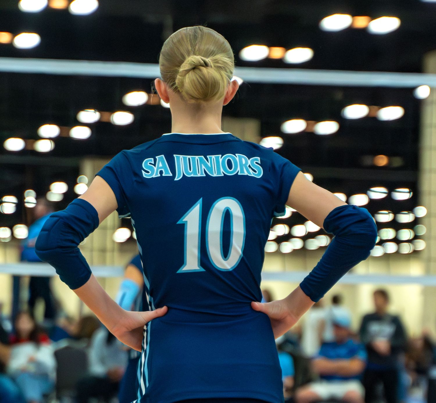 Back view of volleyball players in navy blue jerseys lined up during a match.