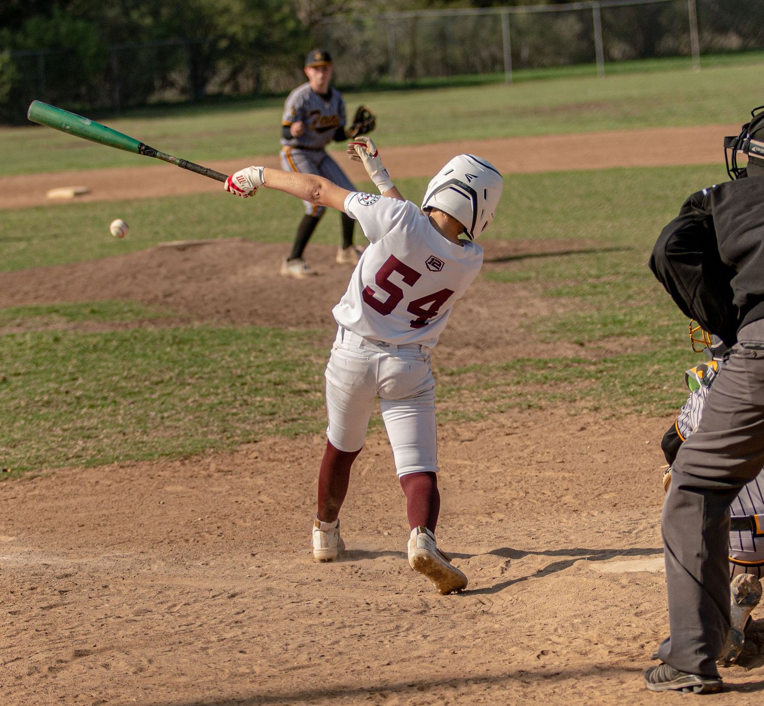 Baseball batter in white uniform number 54 takes swing during game while catcher observes.