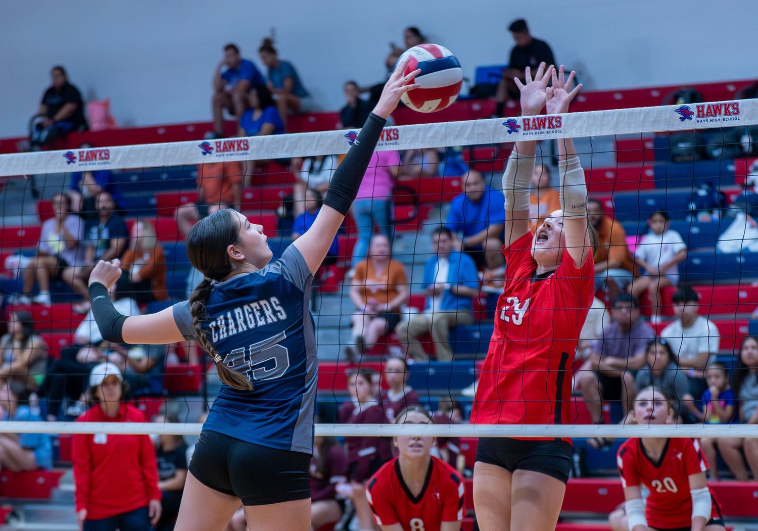 Two players battle at the net during competitive volleyball match.