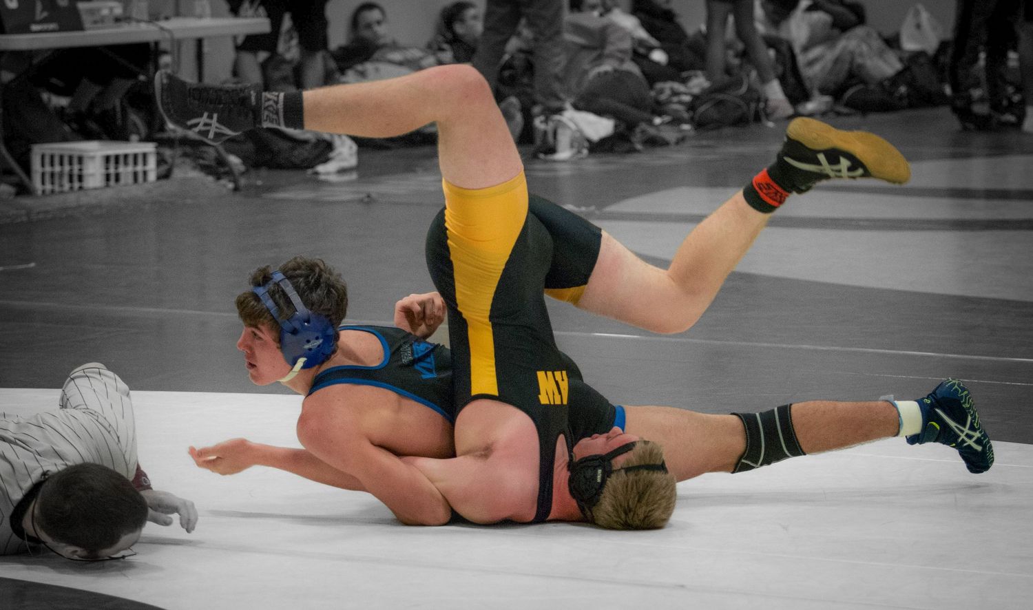 Wrestling competitors engage in ground techniques during an intense match.