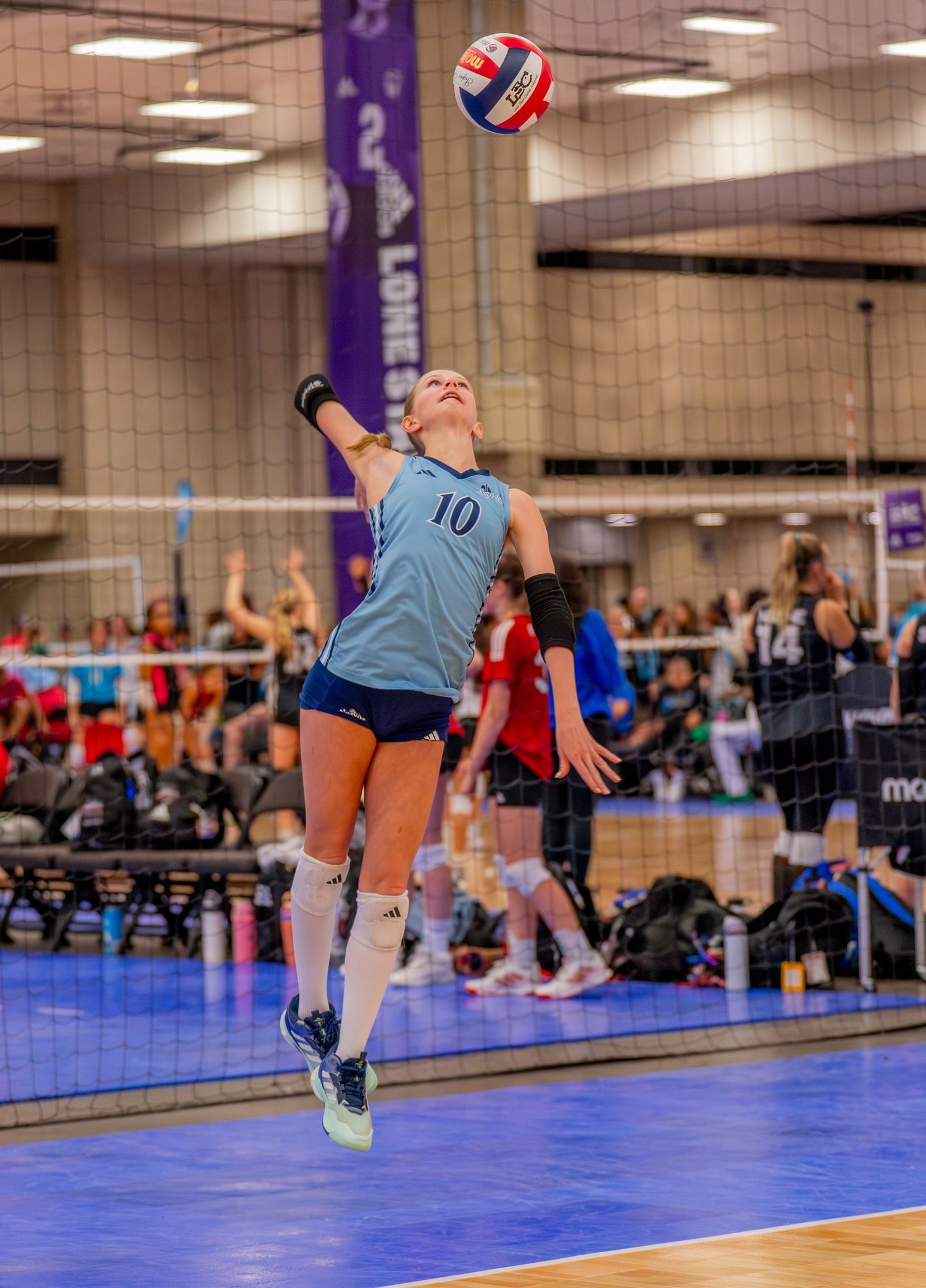 Volleyball players diving and jumping on an indoor court during an intense game sequence.