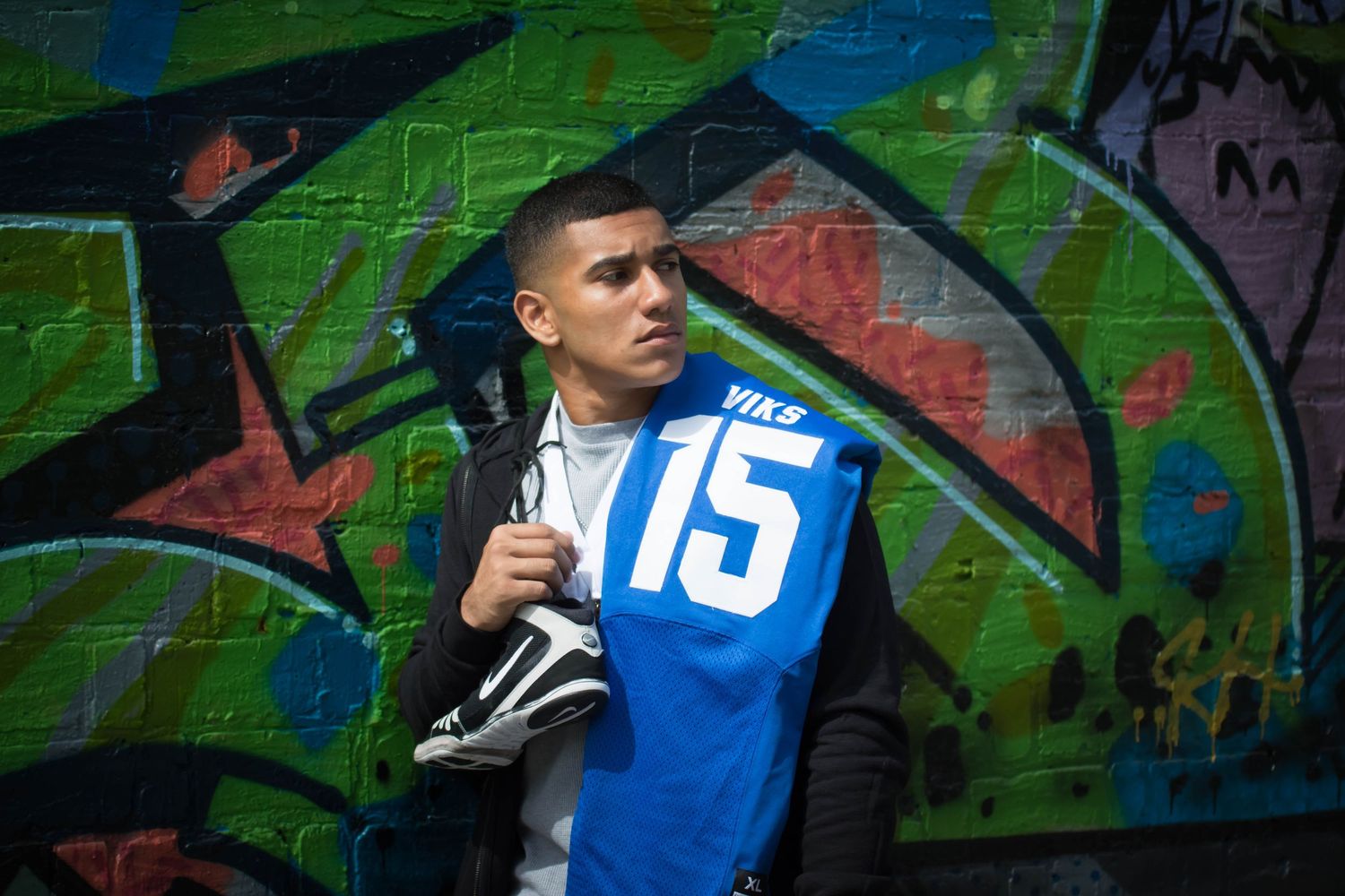 Sports portrait against colorful graffiti wall featuring blue jersey number 15.