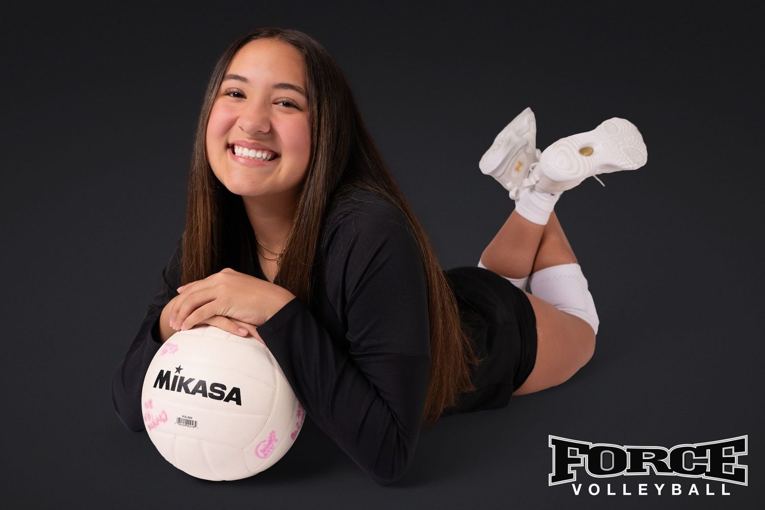 Volleyball player poses with Mikasa ball in black outfit during professional photo session.