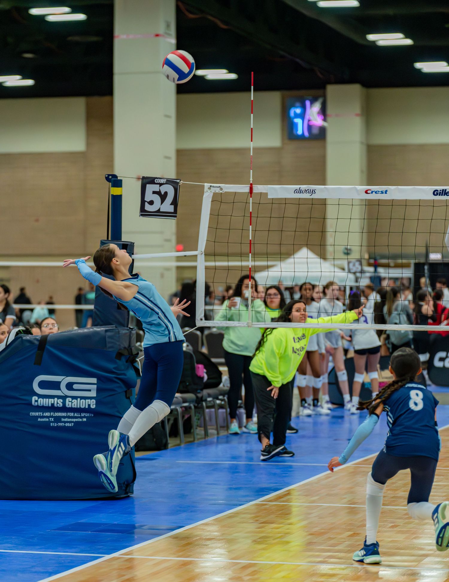 Dynamic volleyball action with players leaping and diving for the ball during tournament play.