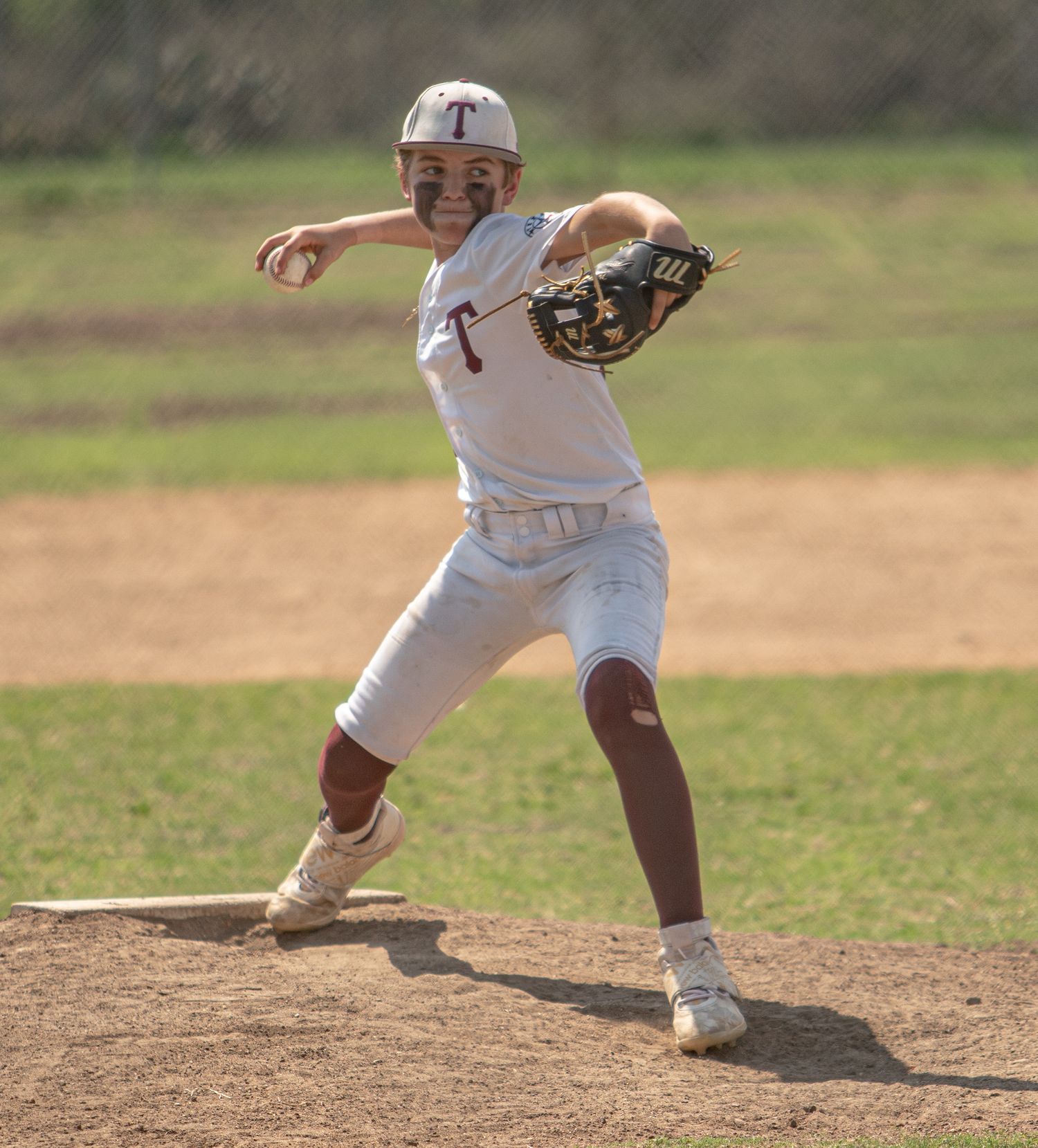 Baseball player in white uniform throws from the pitching mound during a game.