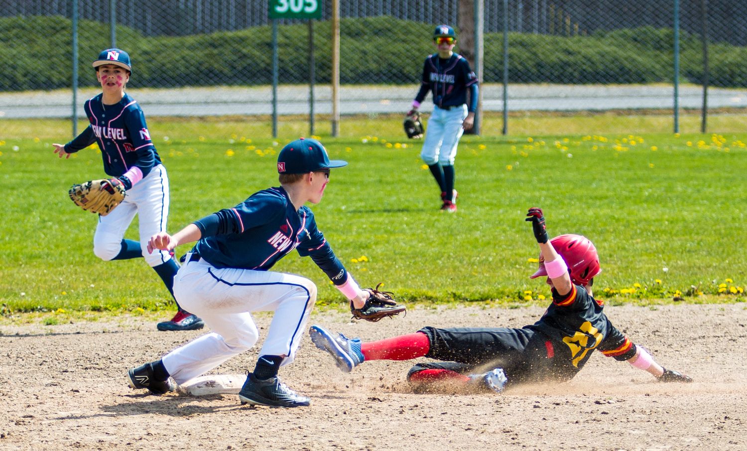 Baseball players execute a sliding play at second base during a game.