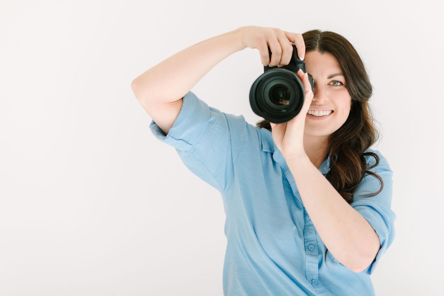 Photographer in light blue shirt takes photos with professional camera from different angles.