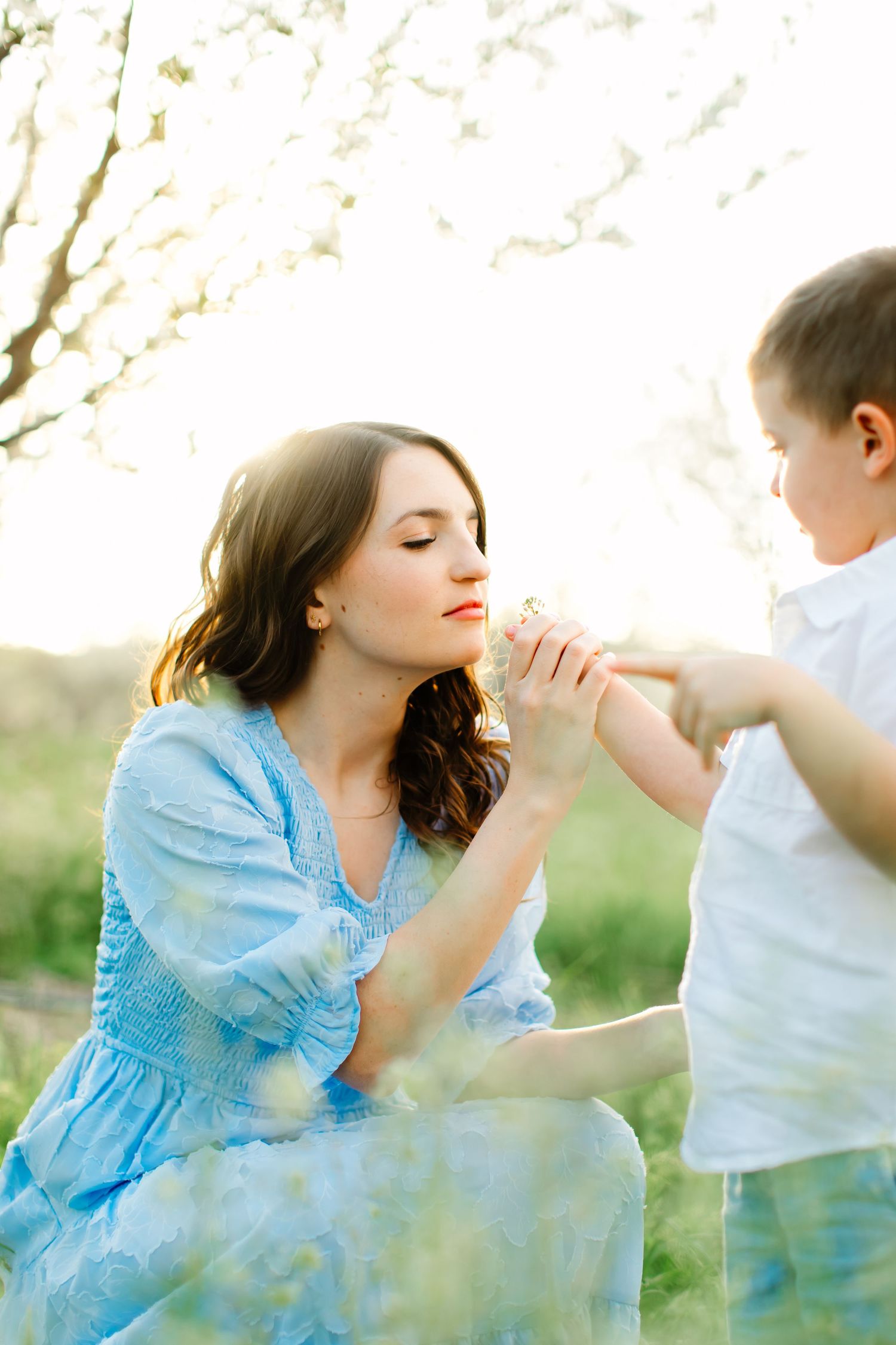 A tender outdoor moment between parent and child with cherry blossoms in the background for their photoshoot in Santaquin, Utah.