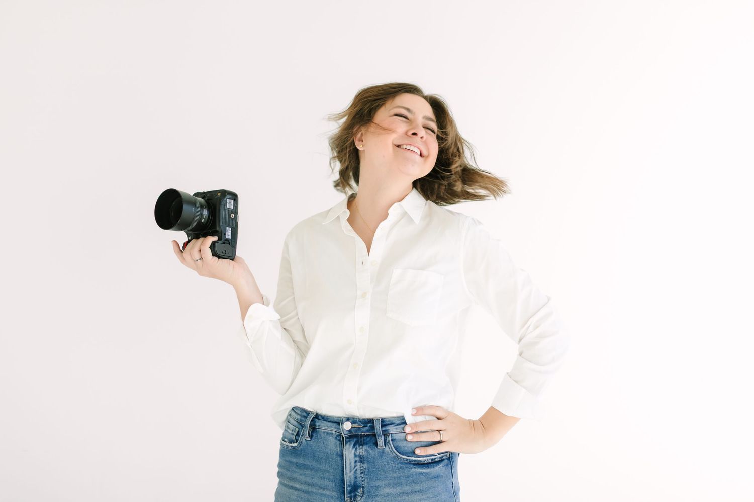 A person in a white button-up shirt and jeans poses against a light background.