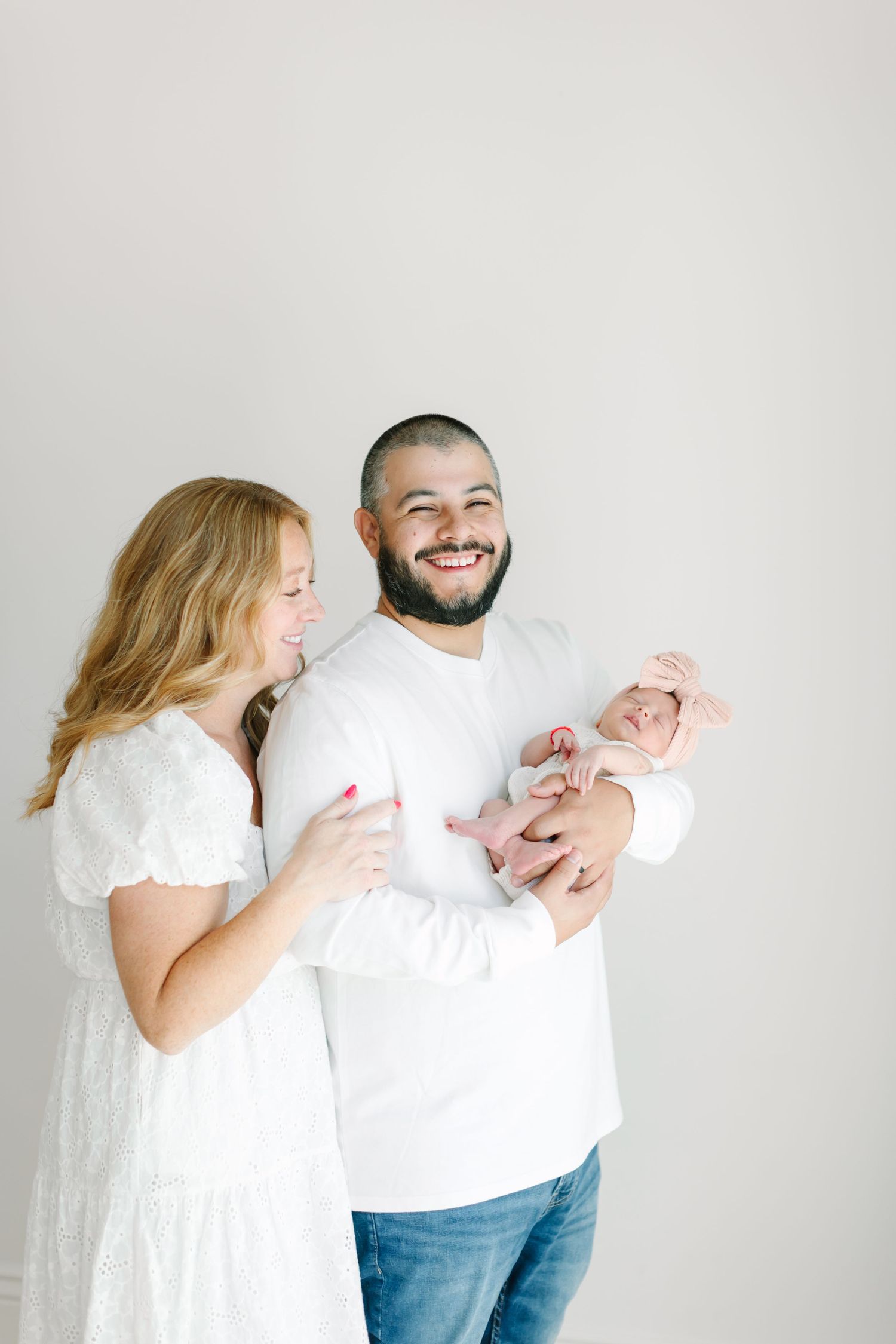 A couple in white clothing share tender moments against a light background in this series of intimate portraits.