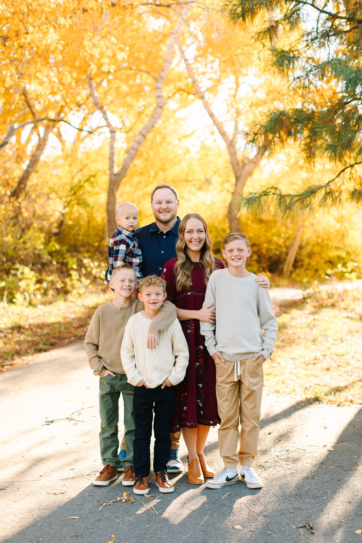 A group sits together on stone steps surrounded by golden autumn foliage during an outdoor photo session.