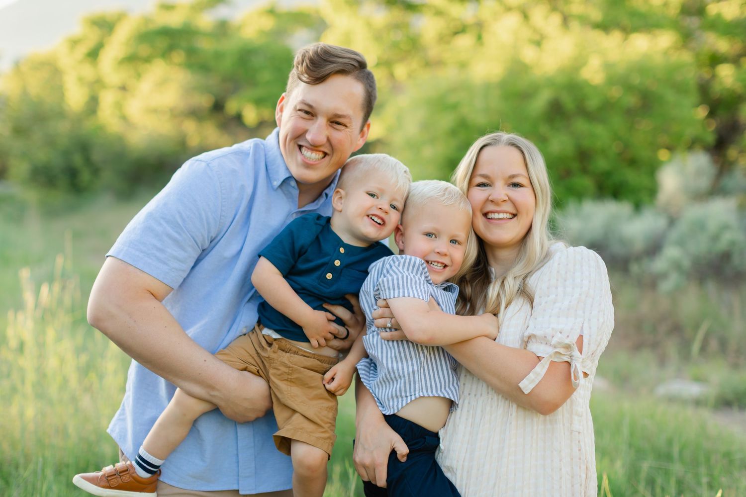 Family members share joyful moments together during an outdoor photo session in a sunlit field.
