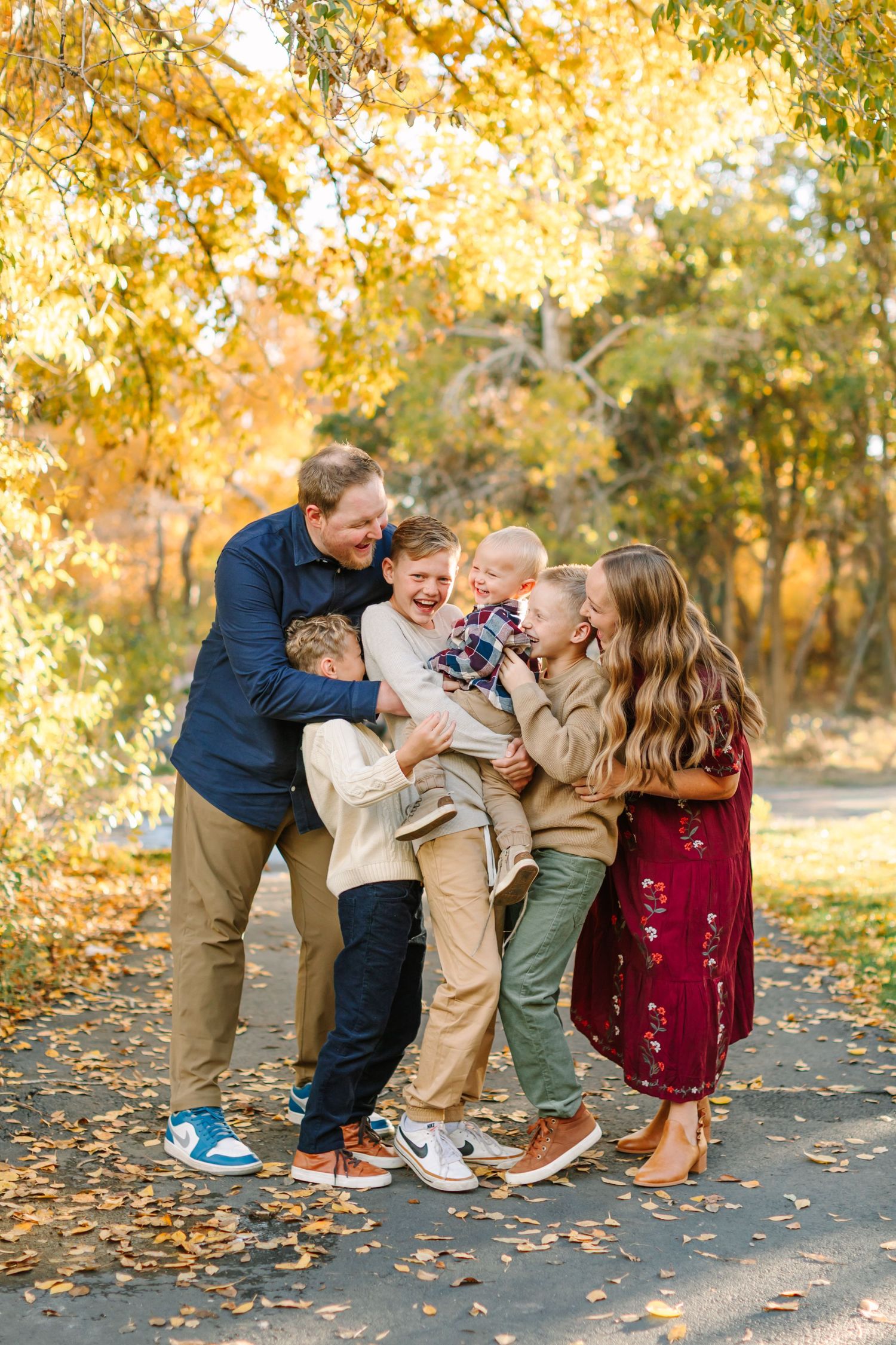 A joyful family shares laughter together on a path surrounded by golden autumn foliage.