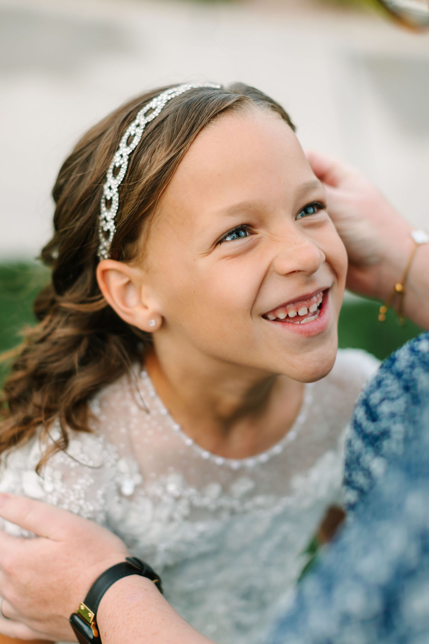A young child laughs joyfully while playing in bubbles wearing a floral headband.