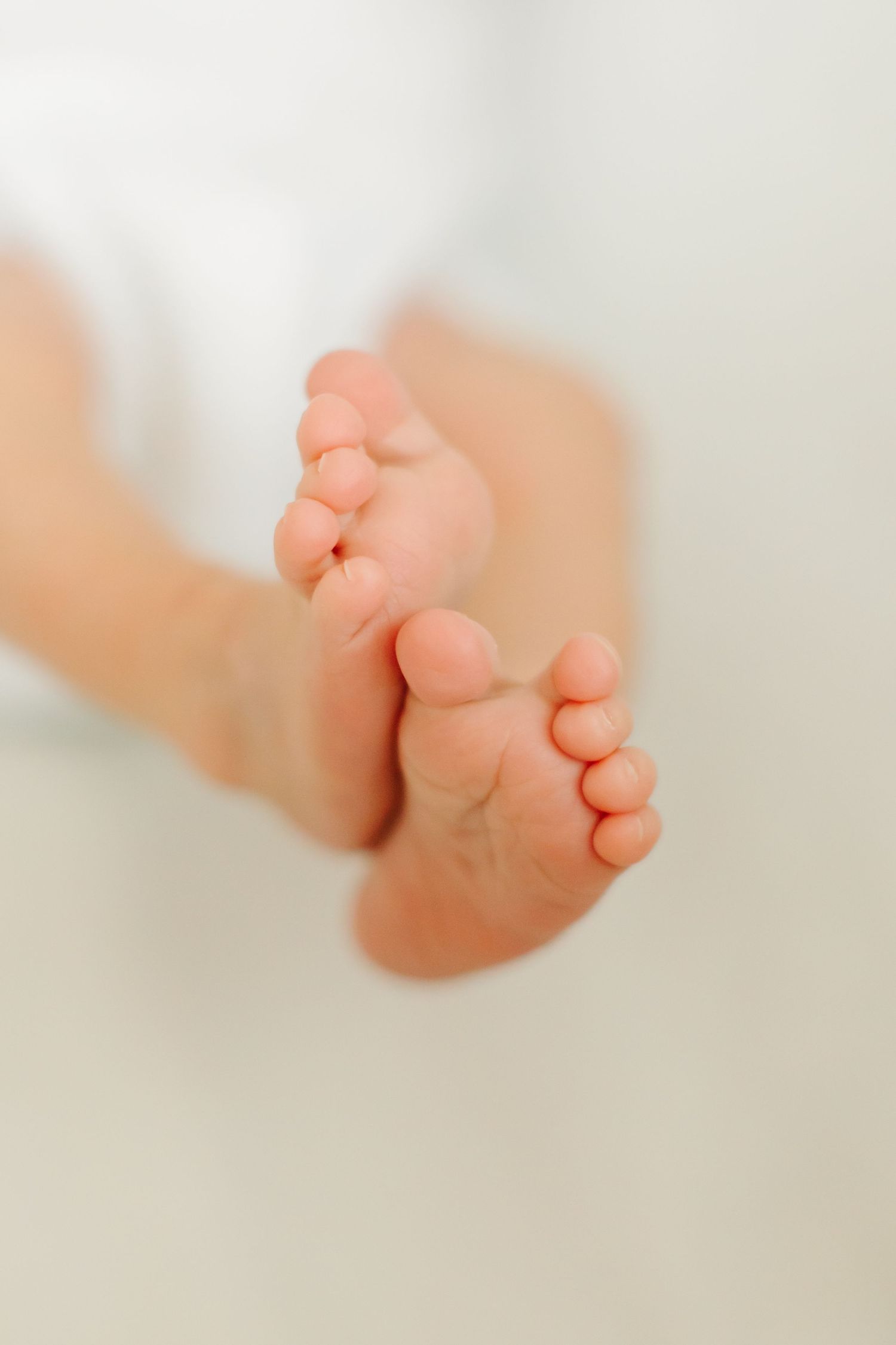 Close-up series of tiny newborn baby feet showing delicate toes against soft white background.