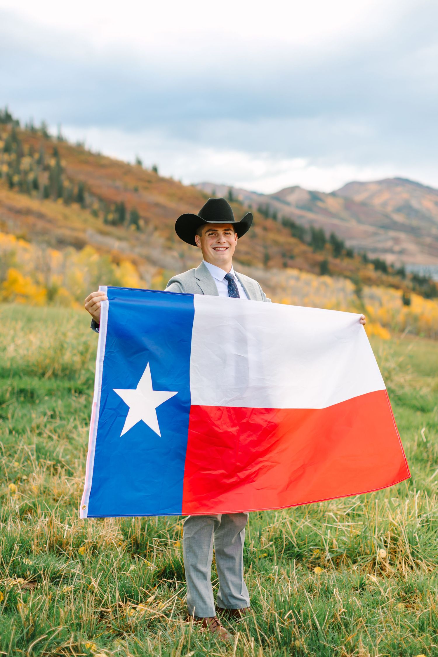 Multiple shots of a Texas state flag being held up against a mountainous autumn landscape.