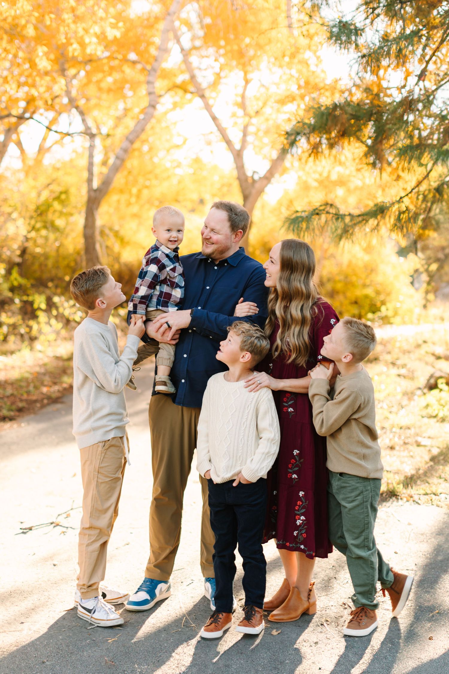 A group shares joyful candid moments in an autumn setting with golden foliage in the background.