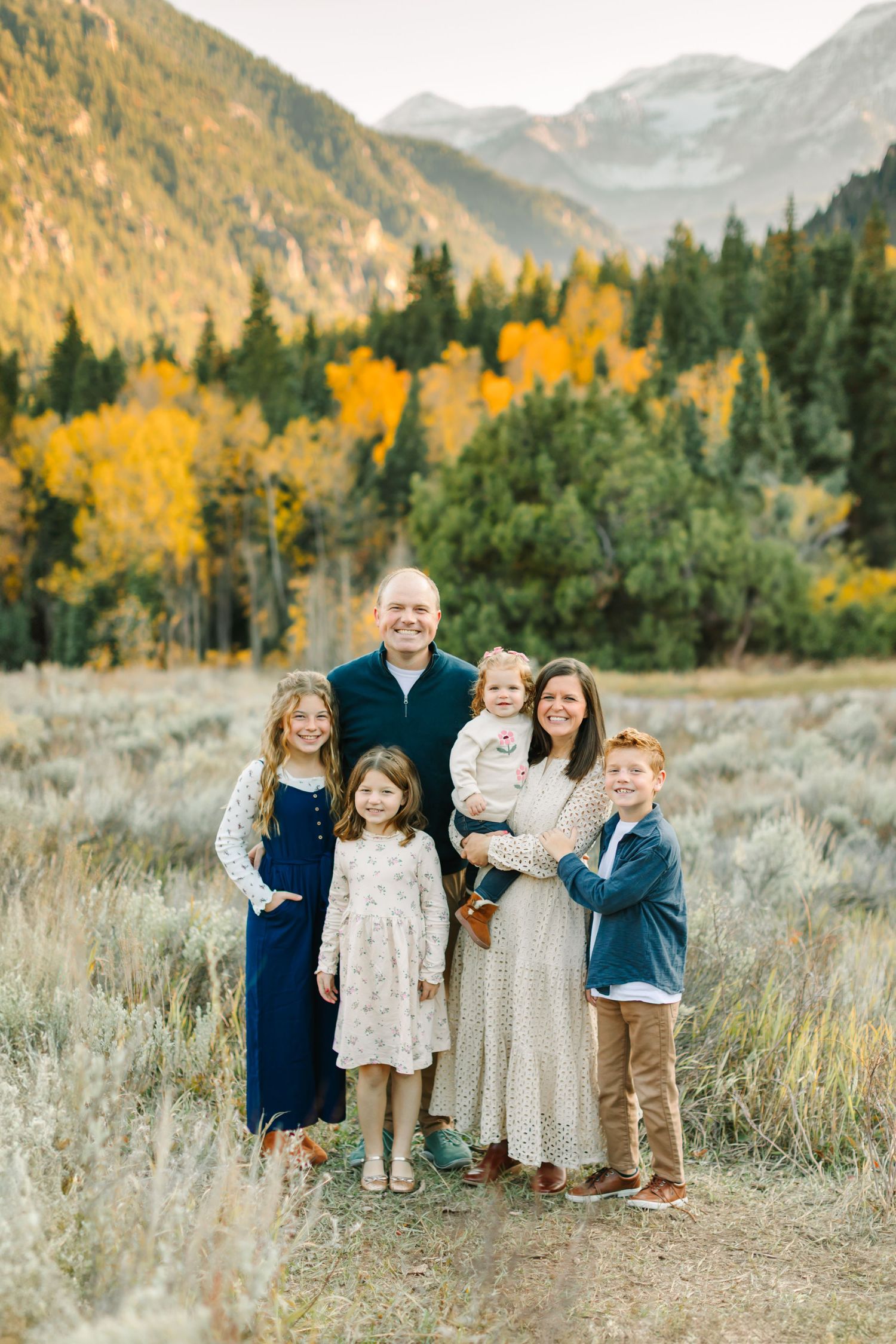 A group stands together in a mountain meadow with golden autumn aspen trees and evergreens in the background.