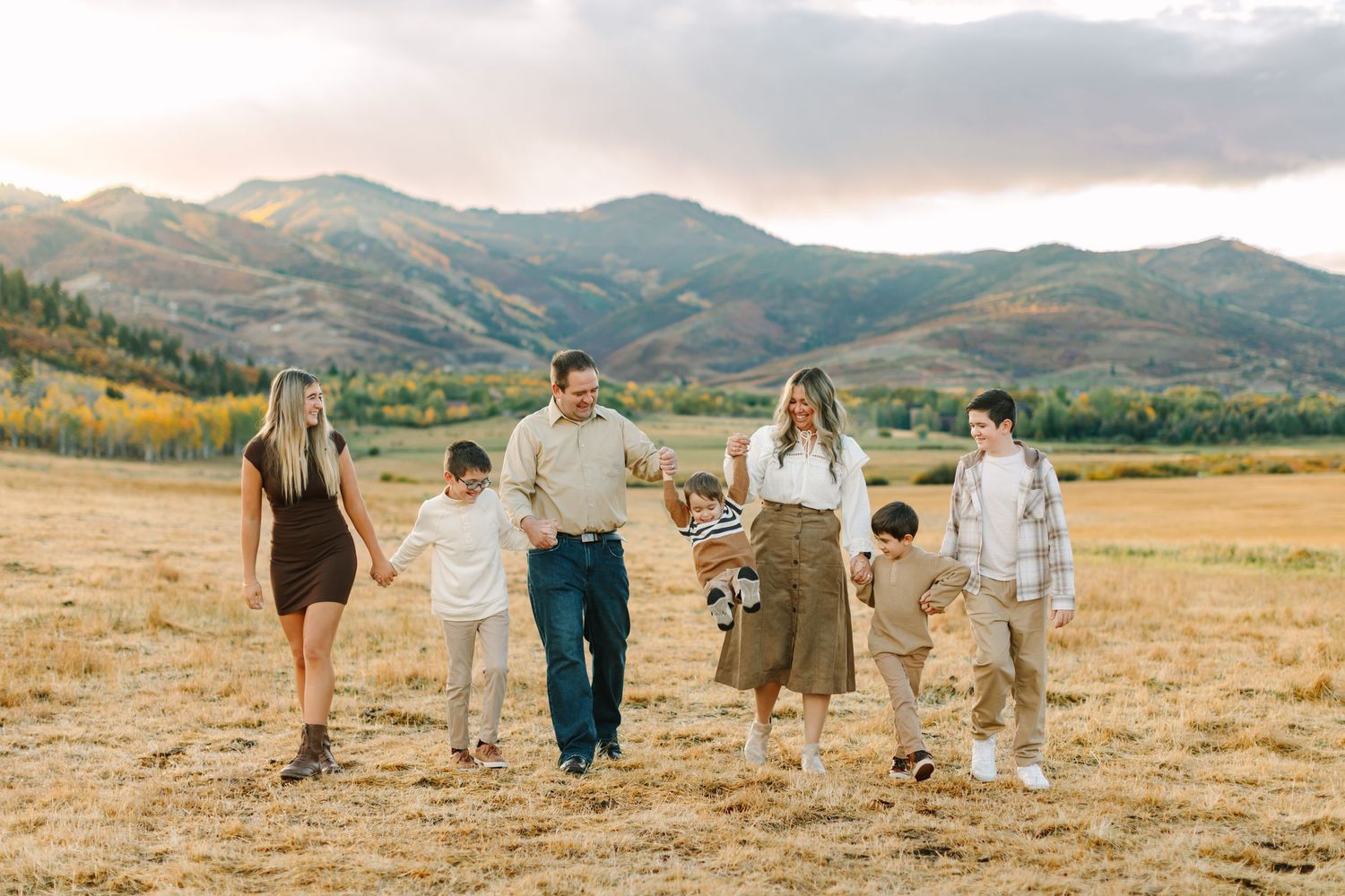 A family walks together in beautiful fall scenery during their family photoshoot in Park City, Utah.