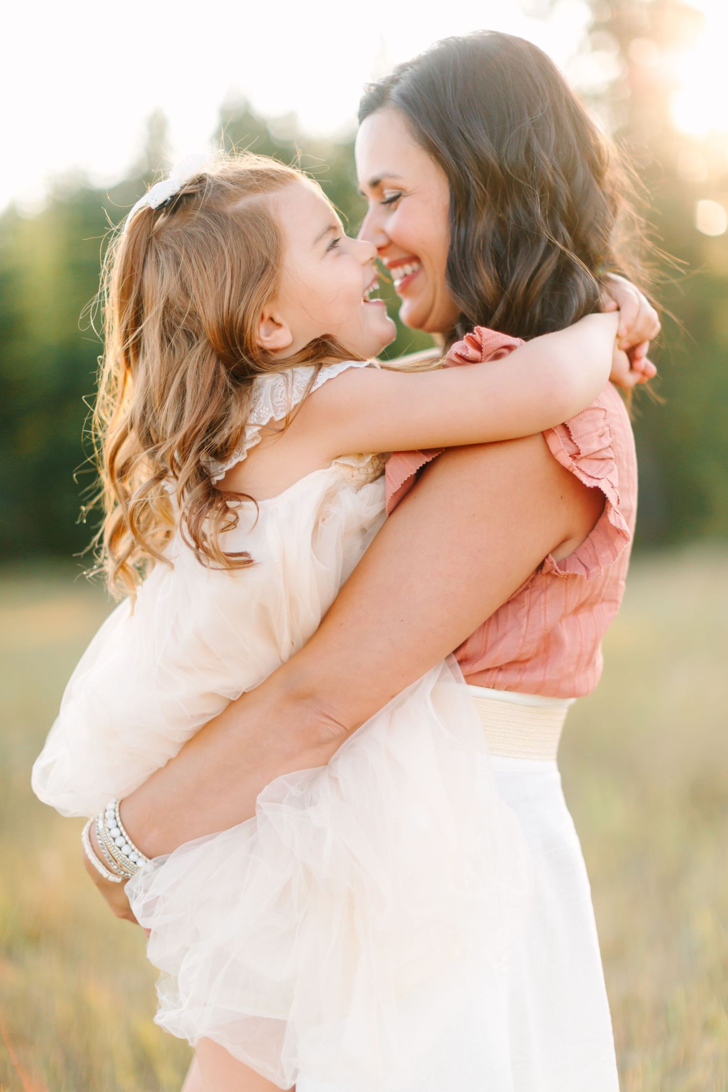 A tender moment captured between parent and child embracing in a sunlit field at golden hour.