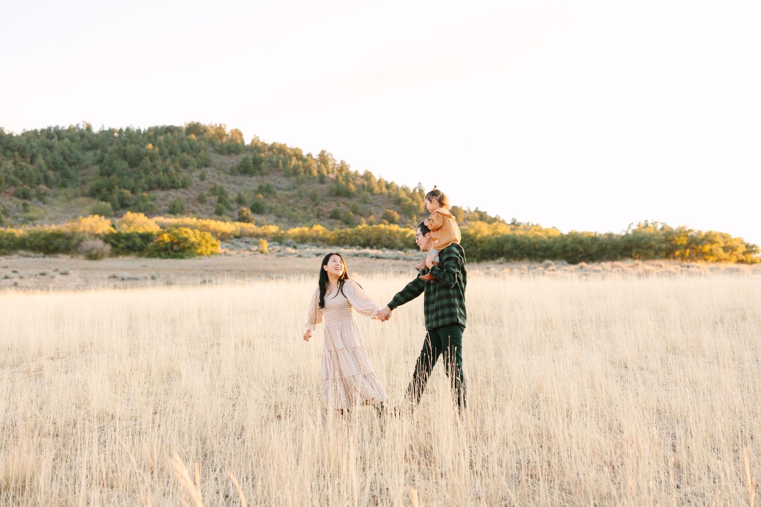 Two figures dance together in a golden sunlit meadow with rolling hills in the background during sunset.