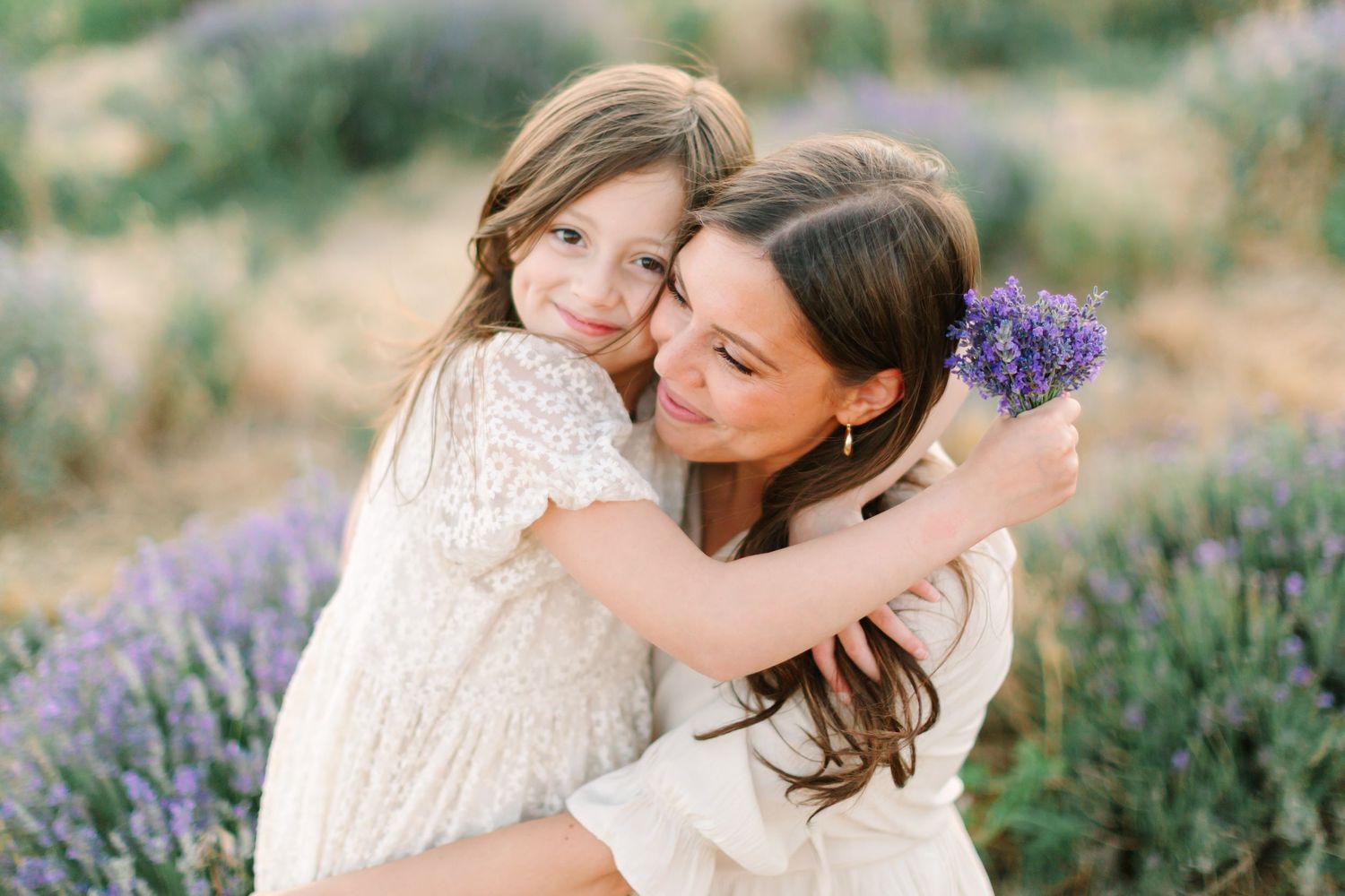 Two people embrace tenderly in a blooming lavender field on a warm summer day.