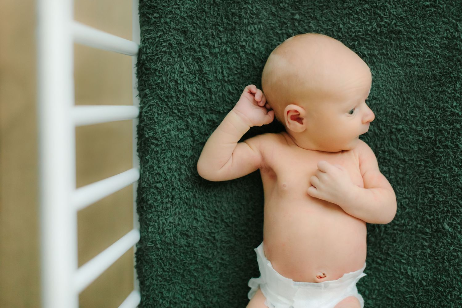 Newborn baby resting on dark green towel shown from different angles.