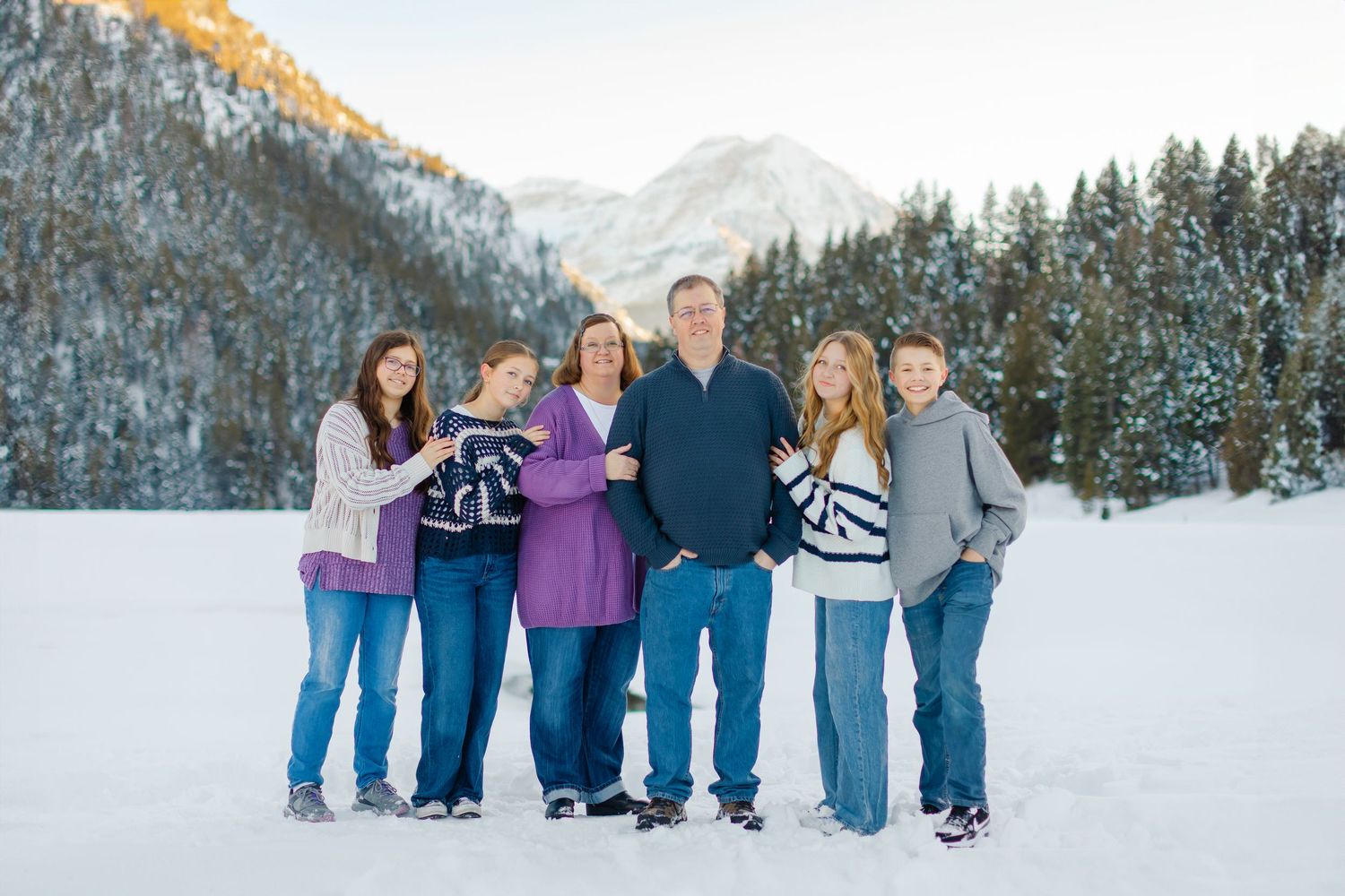 Family photoshoot in snowy mountains with pine trees at Tibble Fork Reservoir in American Fork, Utah in Utah County.