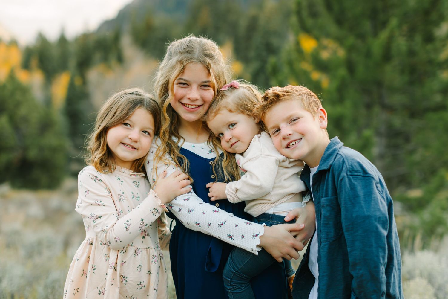 Family members share joyful moments together while posing outdoors in coordinated outfits against a natural backdrop.