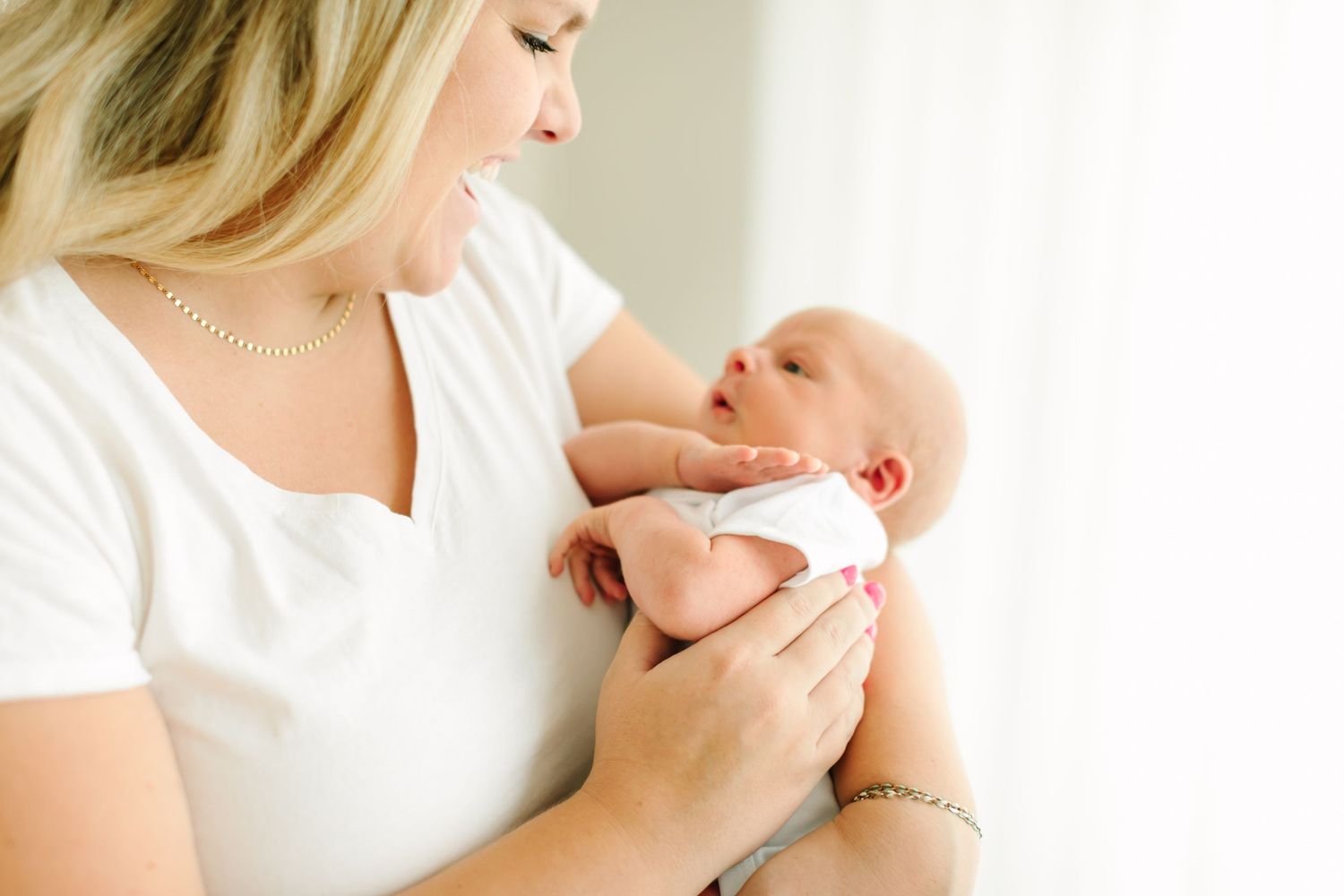 A mother in white holds and nurses her newborn baby in a series of tender breastfeeding moments.