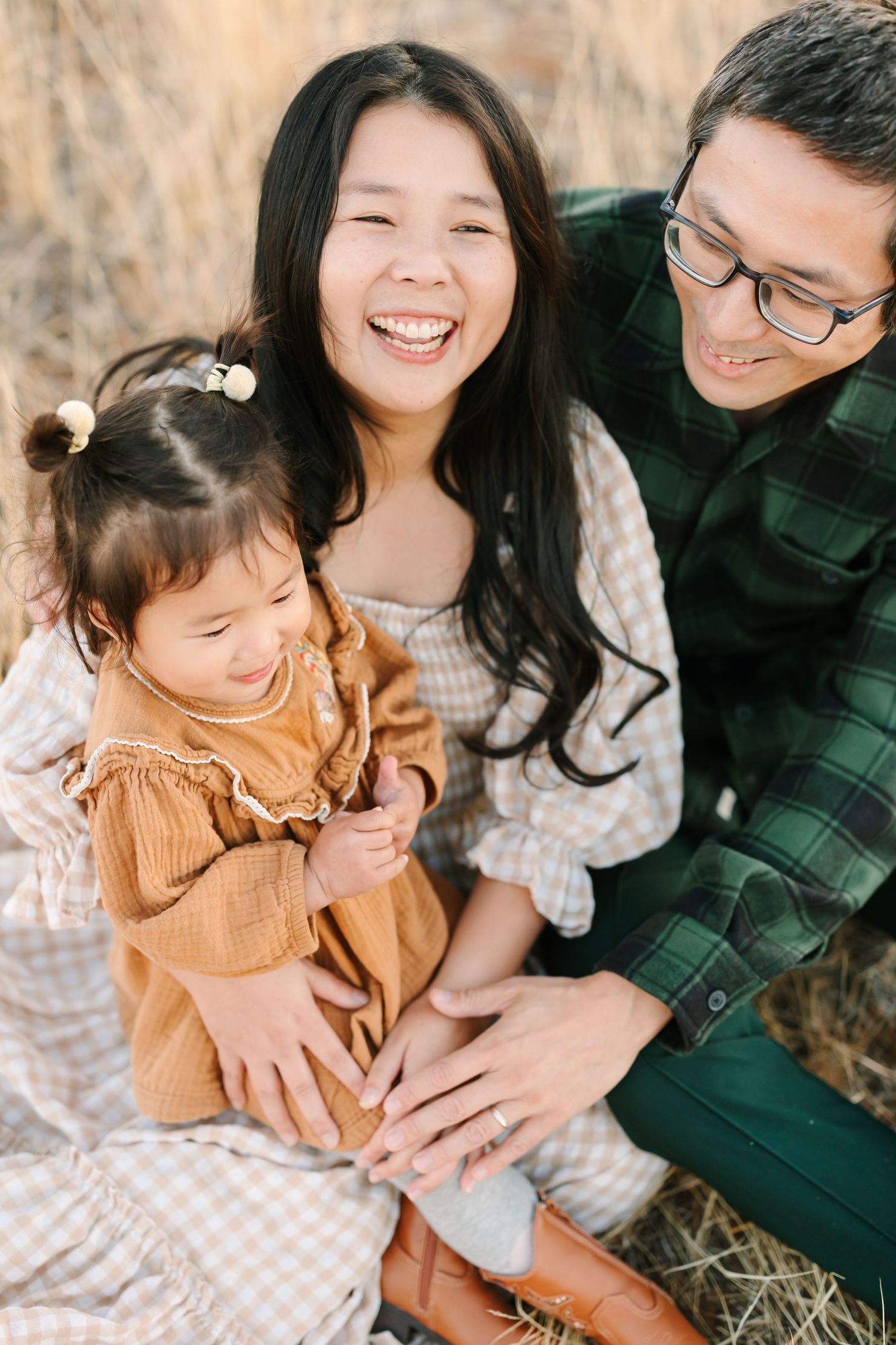A joyful family shares a candid moment together outdoors in casual fall attire.