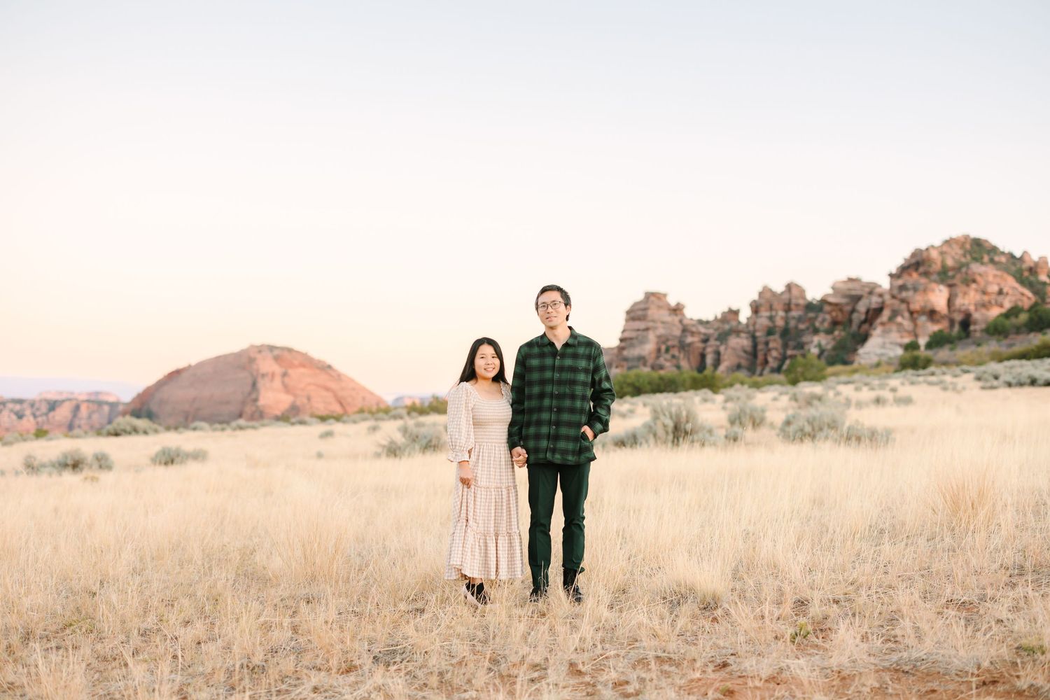 A series of six connected desert landscape photos showing a couple walking through red rock formations at sunset.