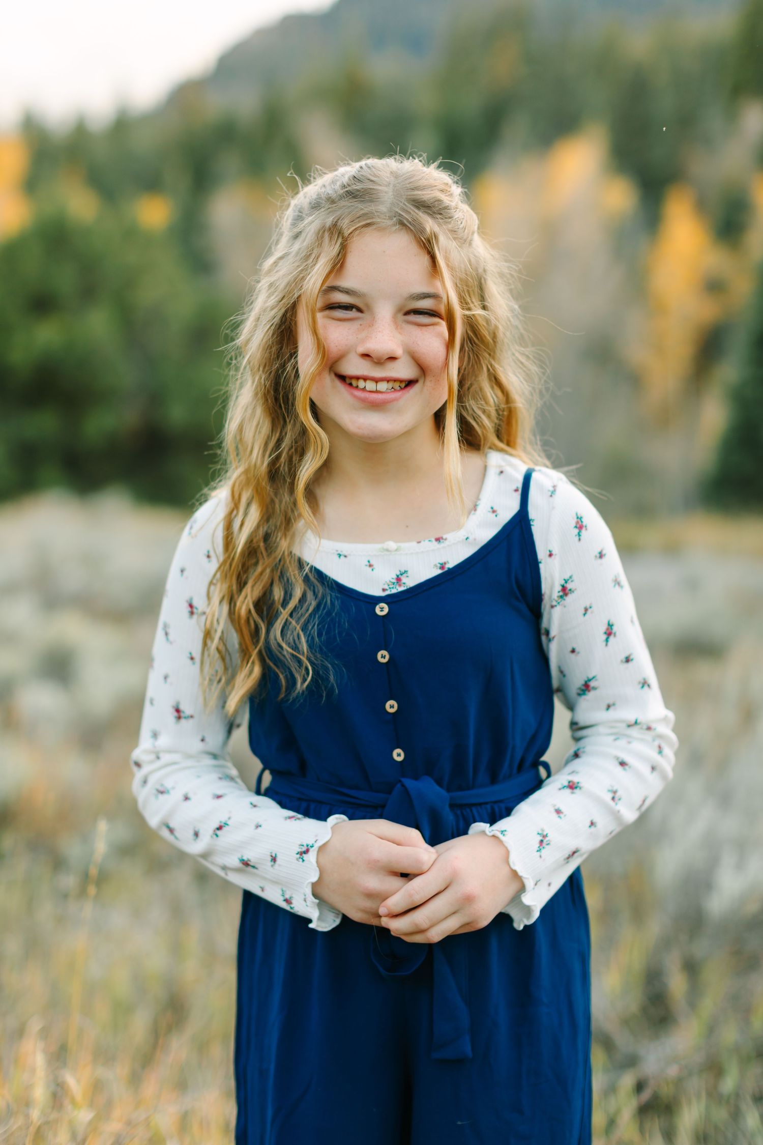 A series of close-up shots in a field showing someone in a navy blue dress with white floral sleeves against an autumn backdrop.