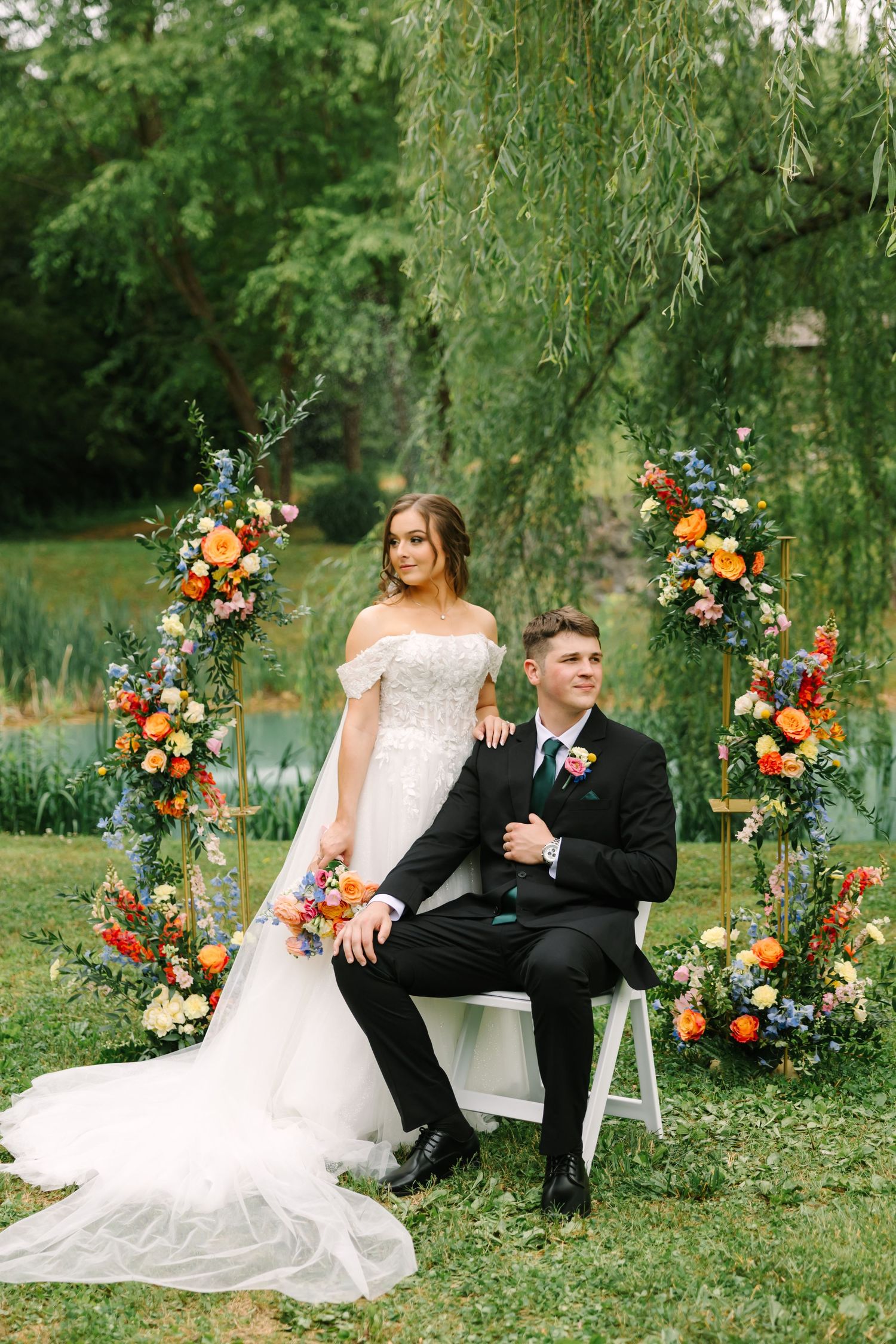 A romantic outdoor wedding scene with floral arch decorations and elegant seating by a pond in a lush garden setting.