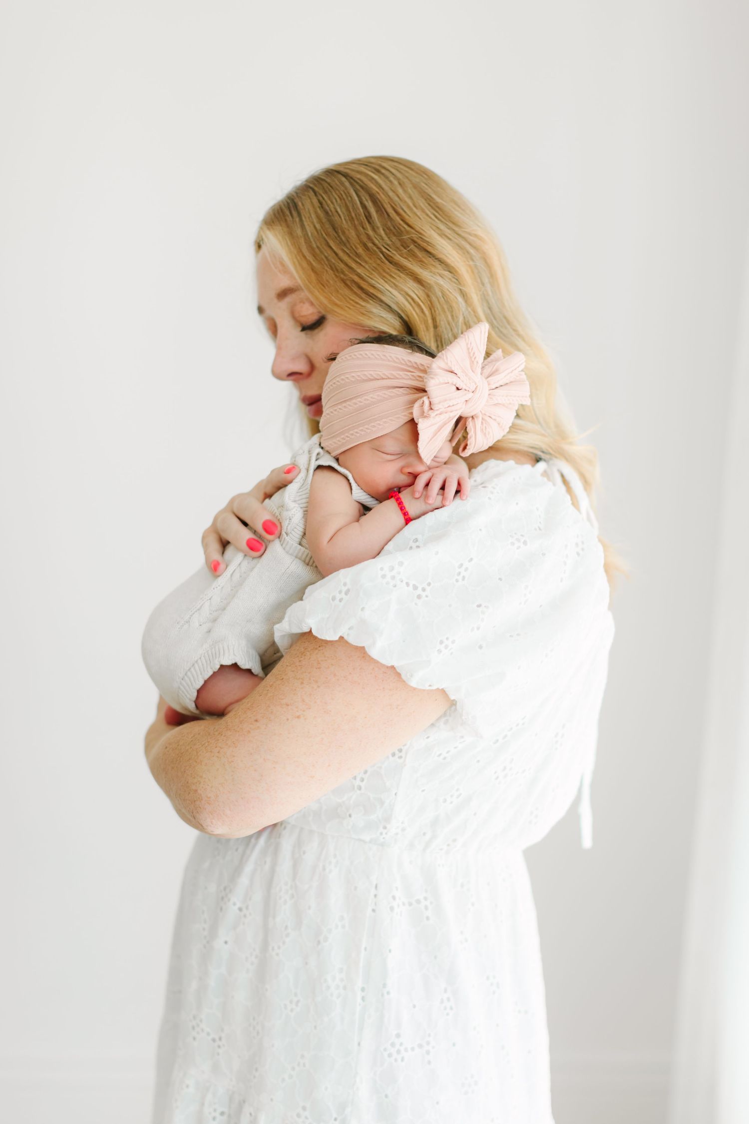 A woman in white embraces someone against a minimalist white backdrop in multiple tender poses.