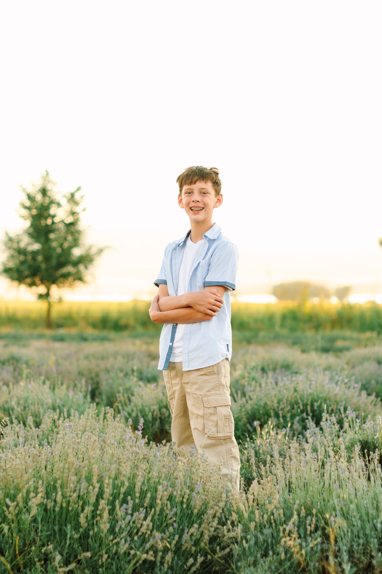 A child stands in a field of lavender flowers during golden hour, creating a peaceful outdoor scene.