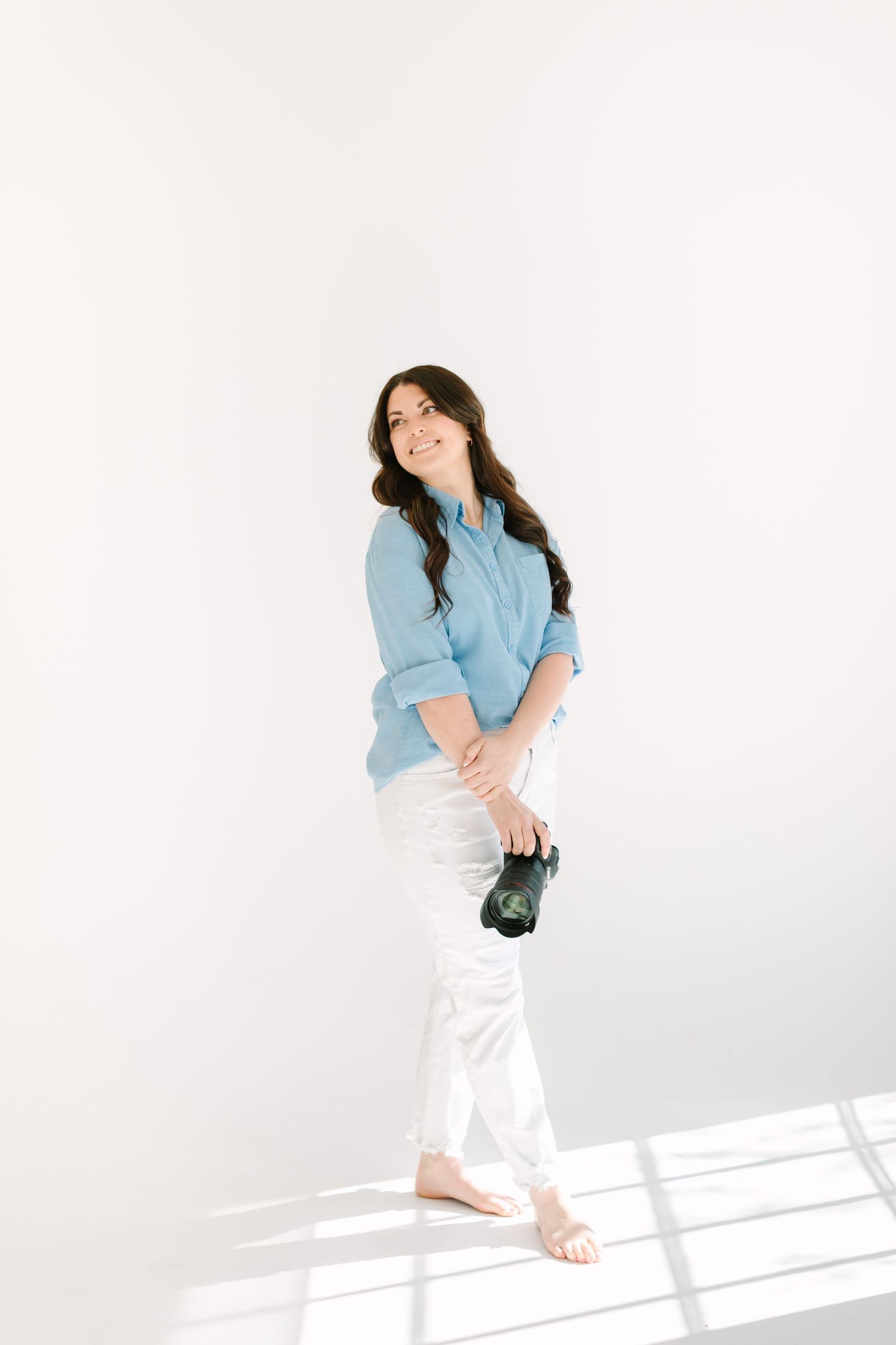 Woman in light blue shirt and white pants dances joyfully against white background in sequence of movement shots.