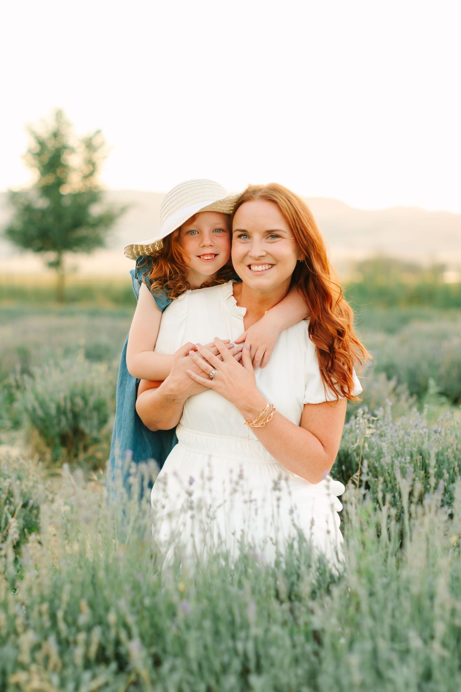 Two people embrace in a sunlit field of lavender and wildflowers during a summer photoshoot.
