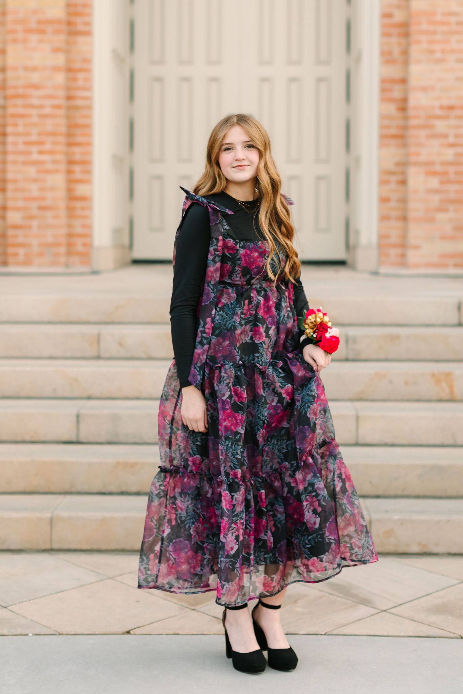 A floral black and pink dress with tulle skirt is showcased in a multi-panel photo against a brick building backdrop.