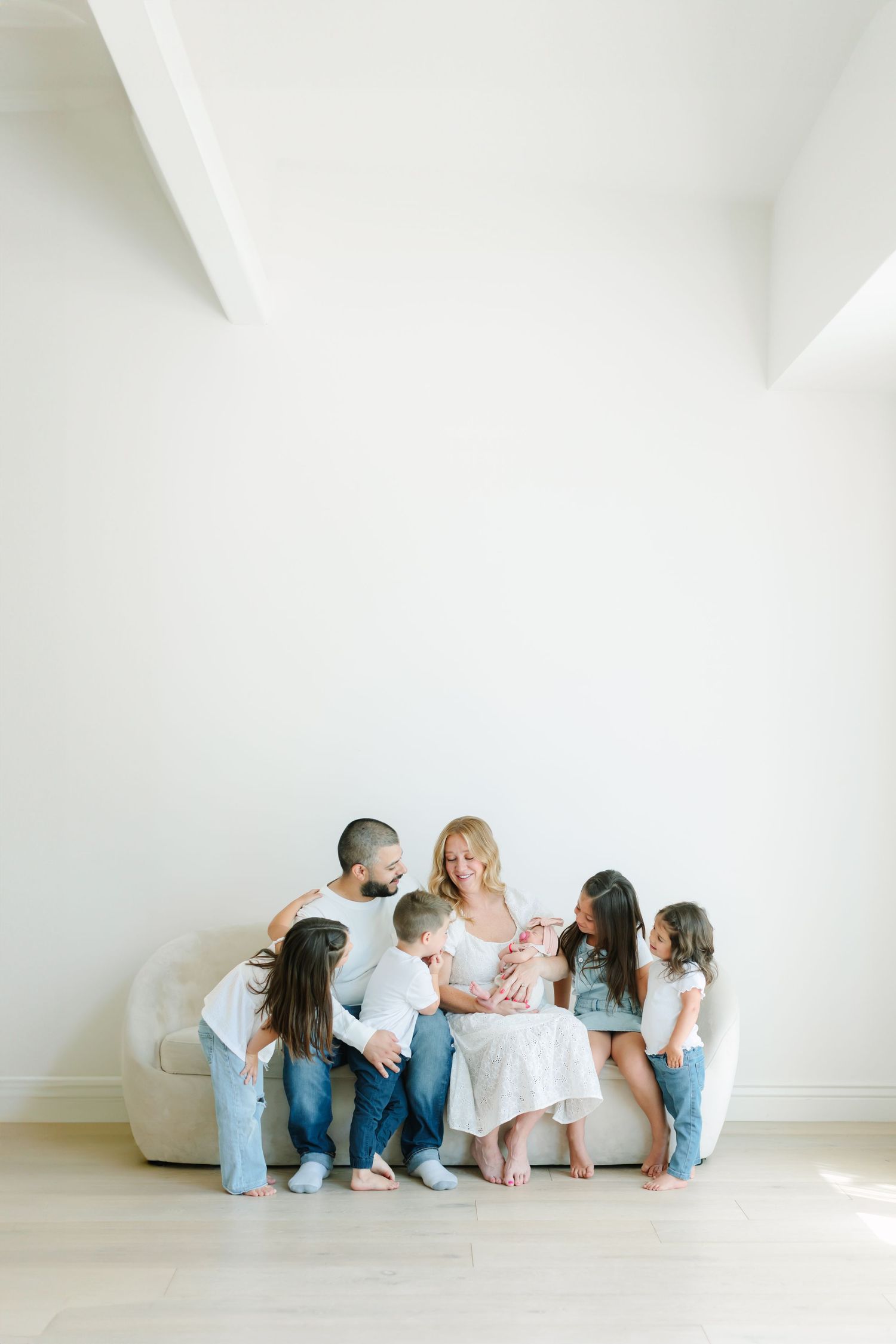Family sitting together against white wall wearing coordinated blue and white outfits.